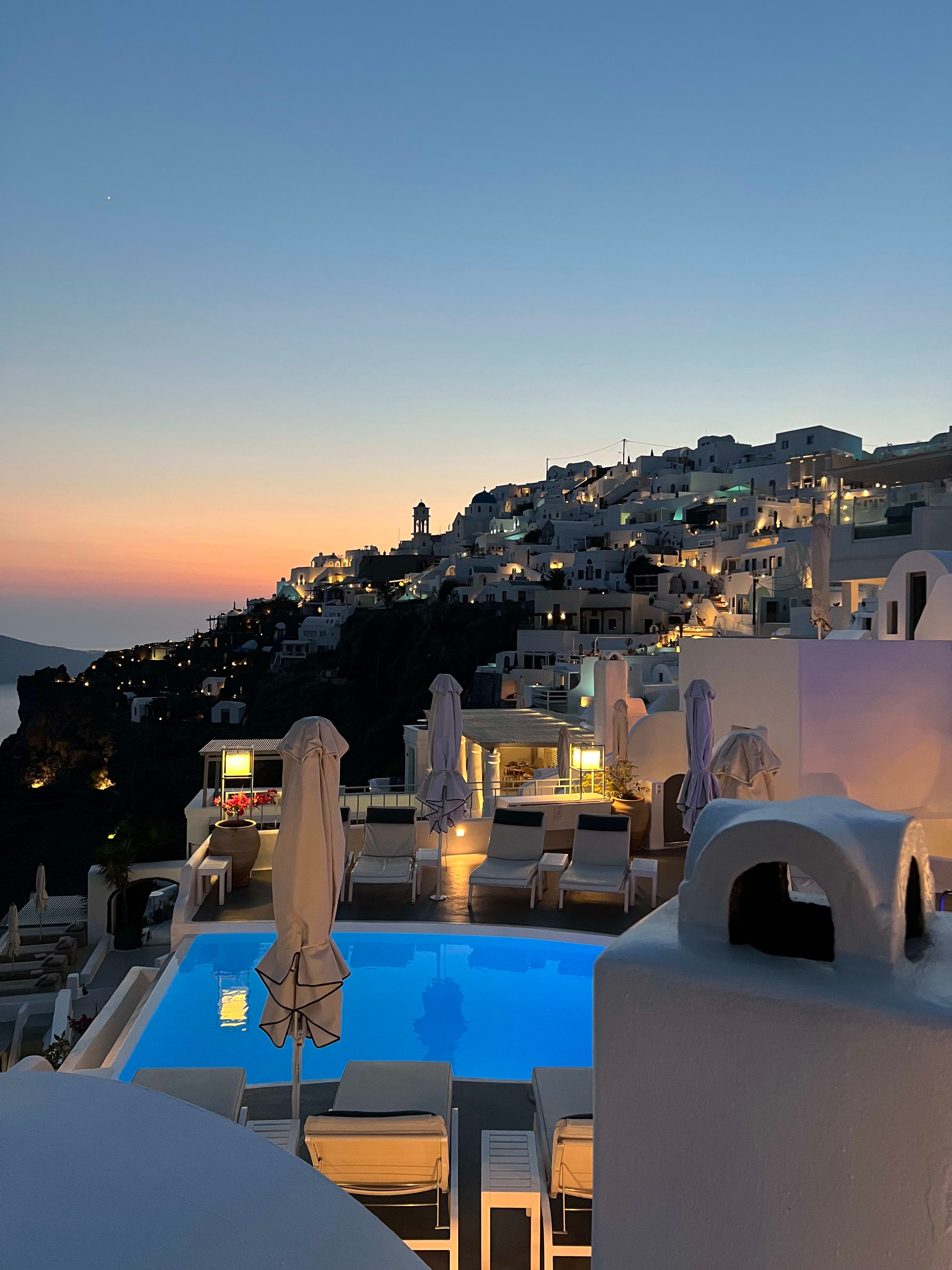View of a pool in Santorini looking out over the houses at sunset