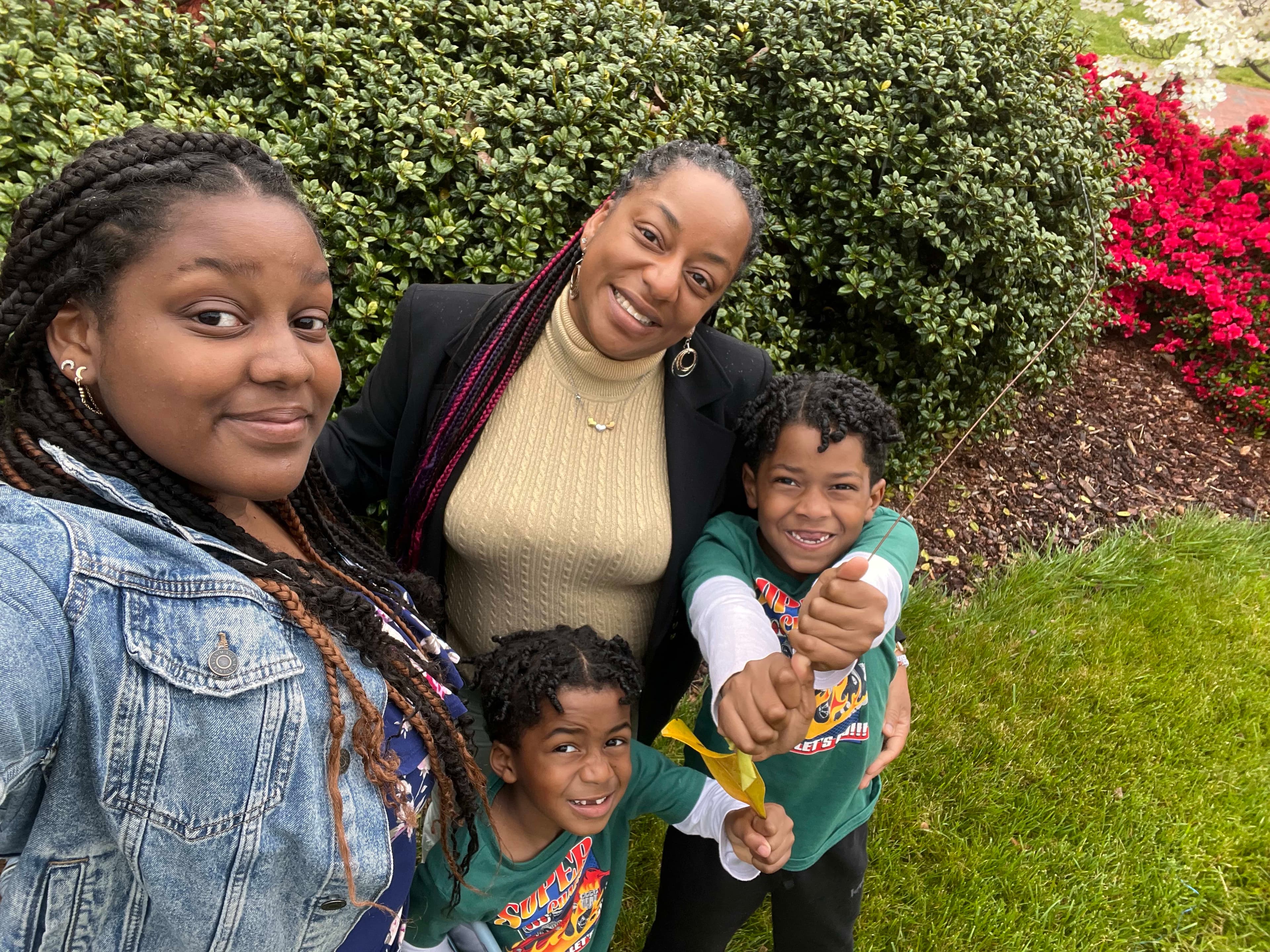Ashley wearing a turtleneck posing for a photo outside in a yard with children