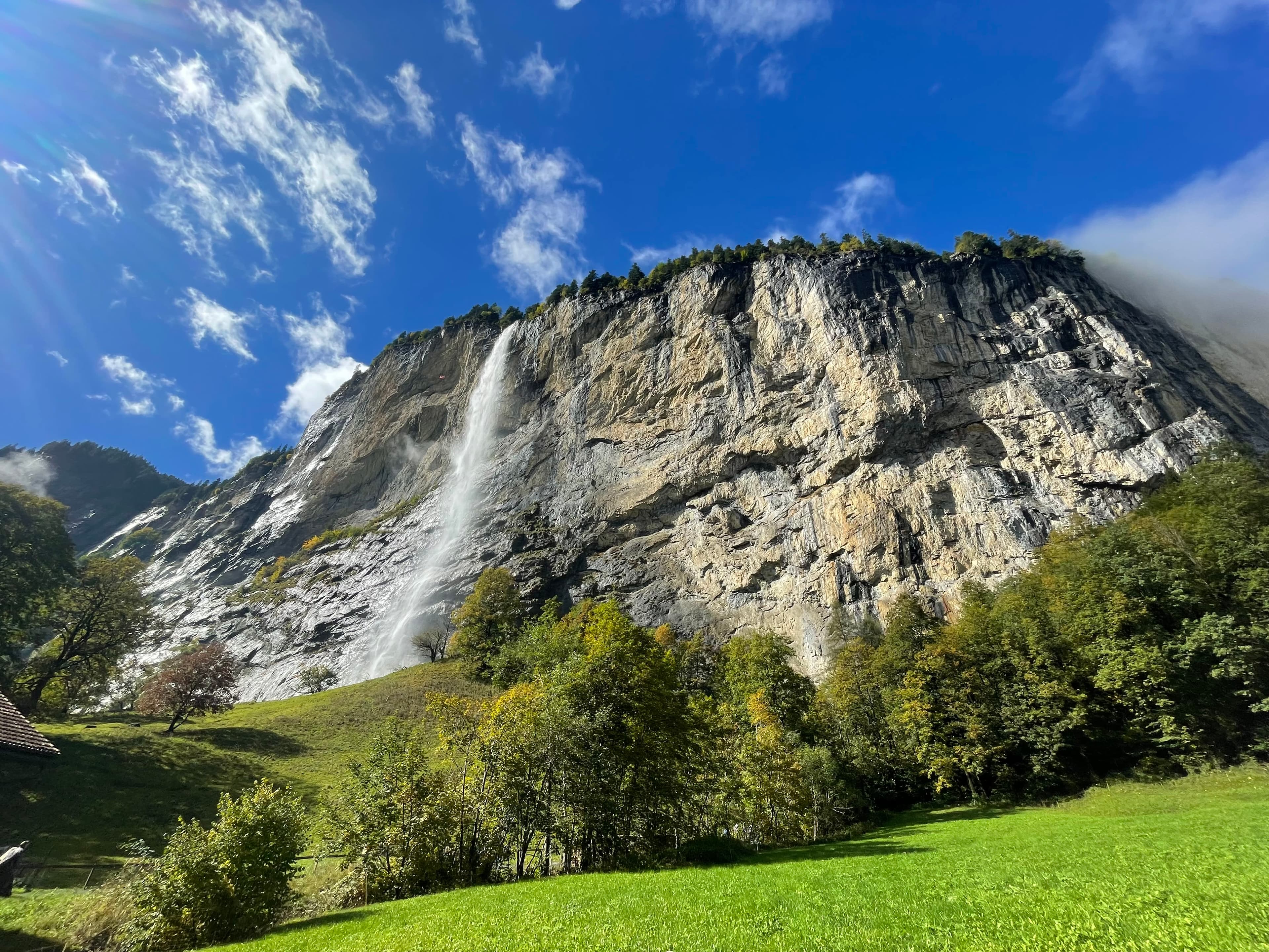 Beautiful view from the bottom of Staubbach waterfall surrounded by lush greenery on a sunny day