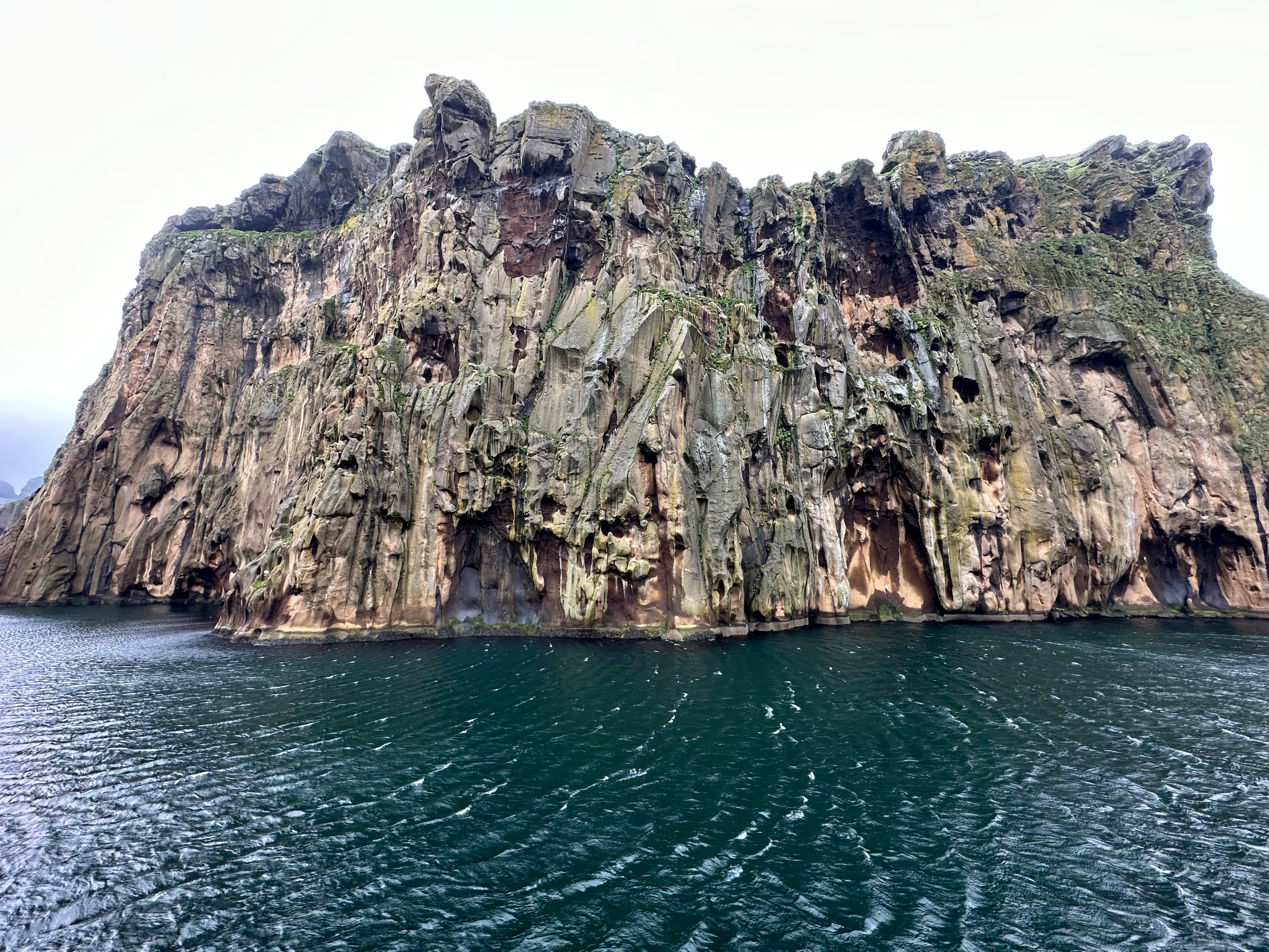Beautiful view of a large rock formation emerging from a dark sea on a cloudy day
