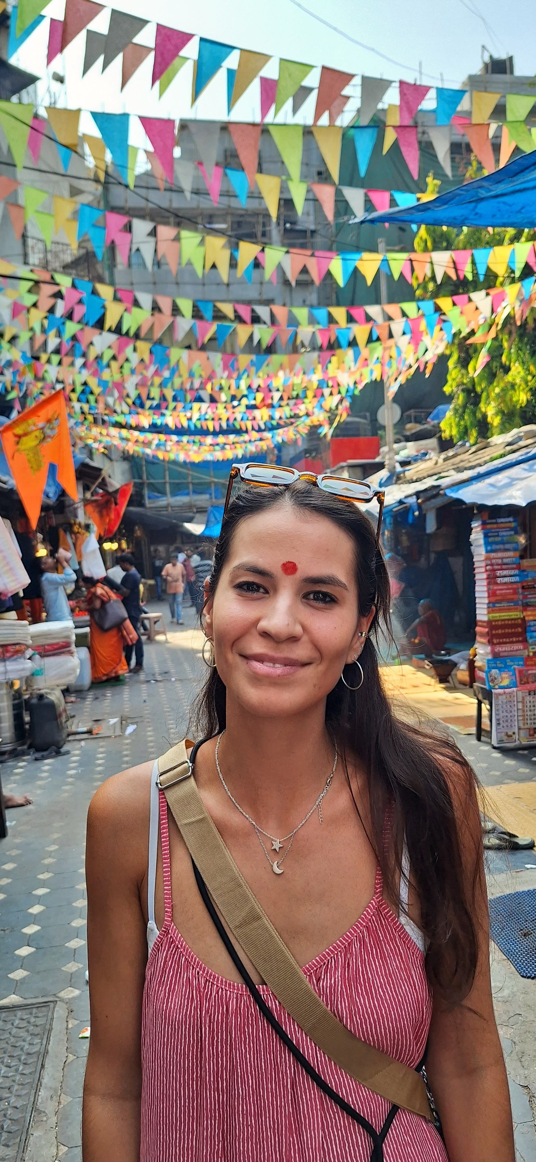 Picture of Marianna wearing a pink tank top and posing on a street decorated with colorful flags