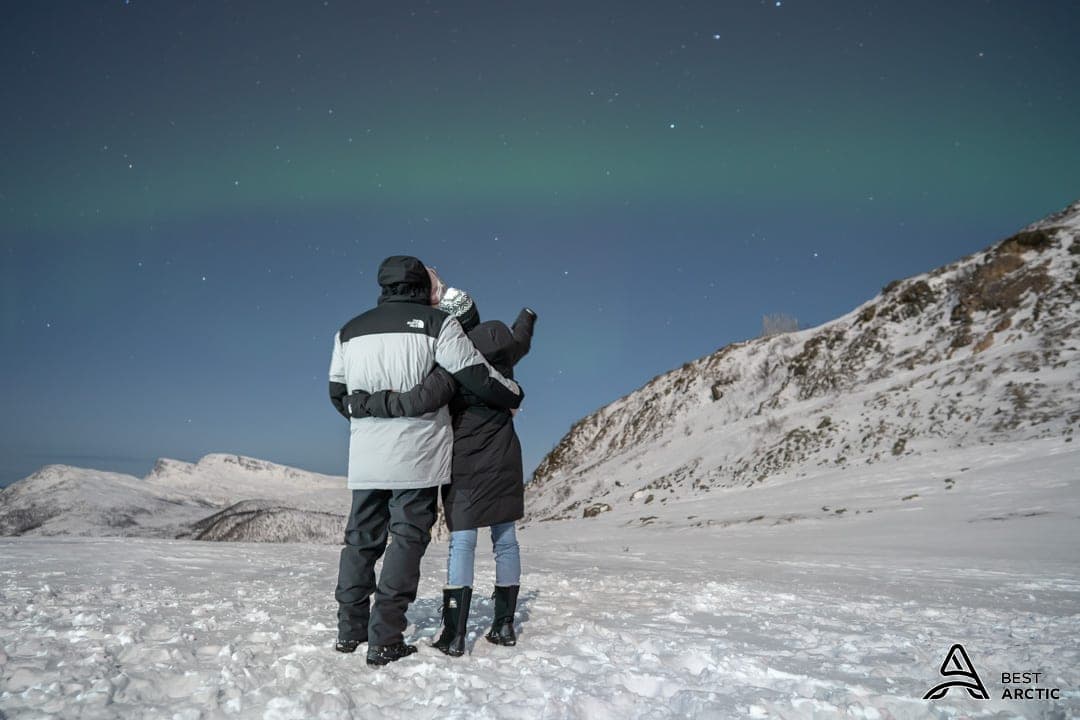 Picture of Dayna with her arm around someone watching the northern lights in a snowy place