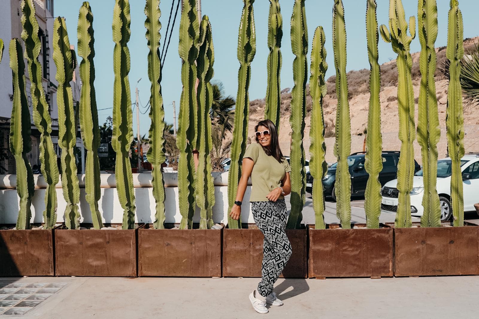 Rachael, posing in front of a wall of tall, thin cacti.