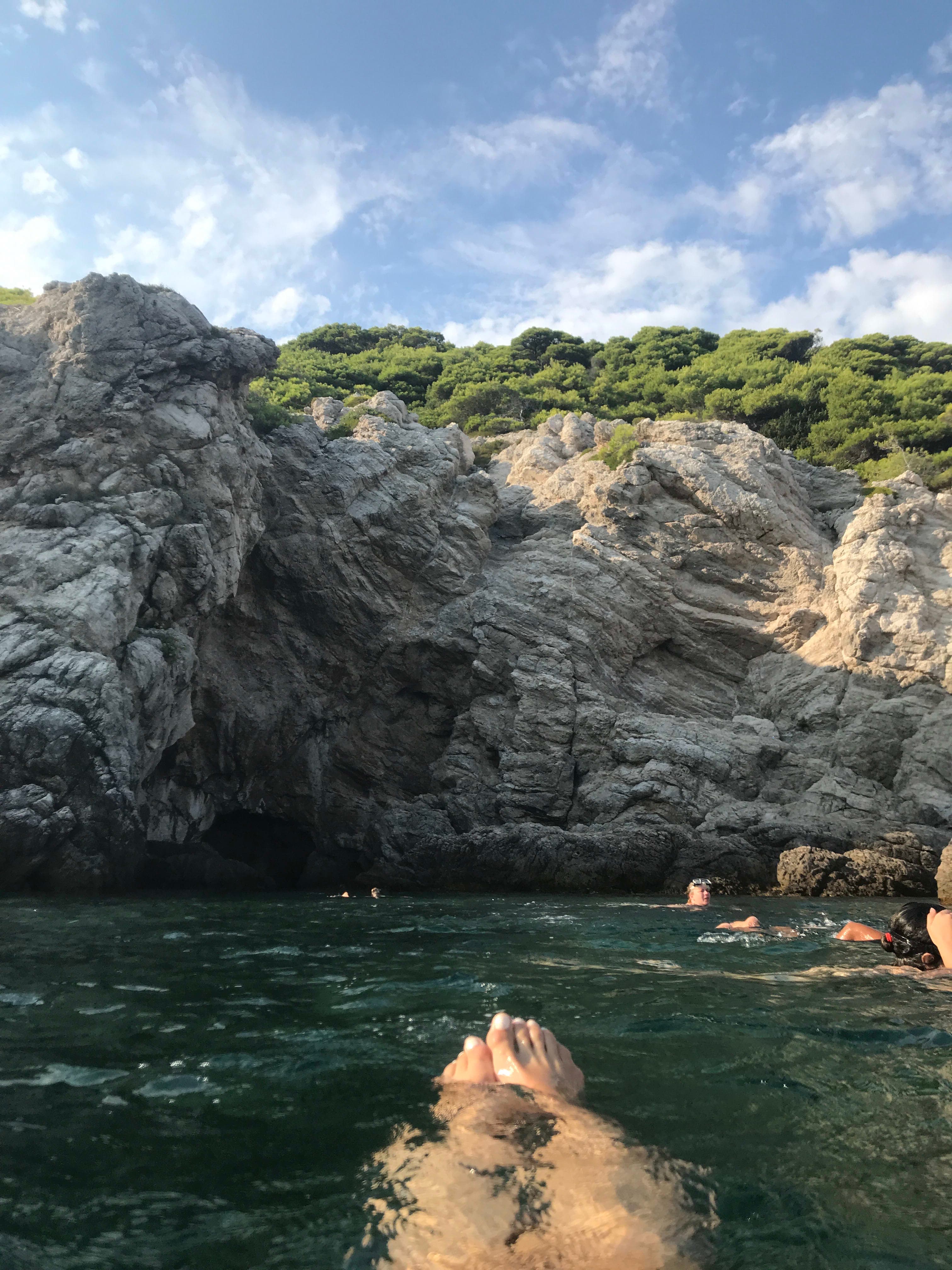 A person's toes floating in clear blue water with a view of the mountains ahead of them.