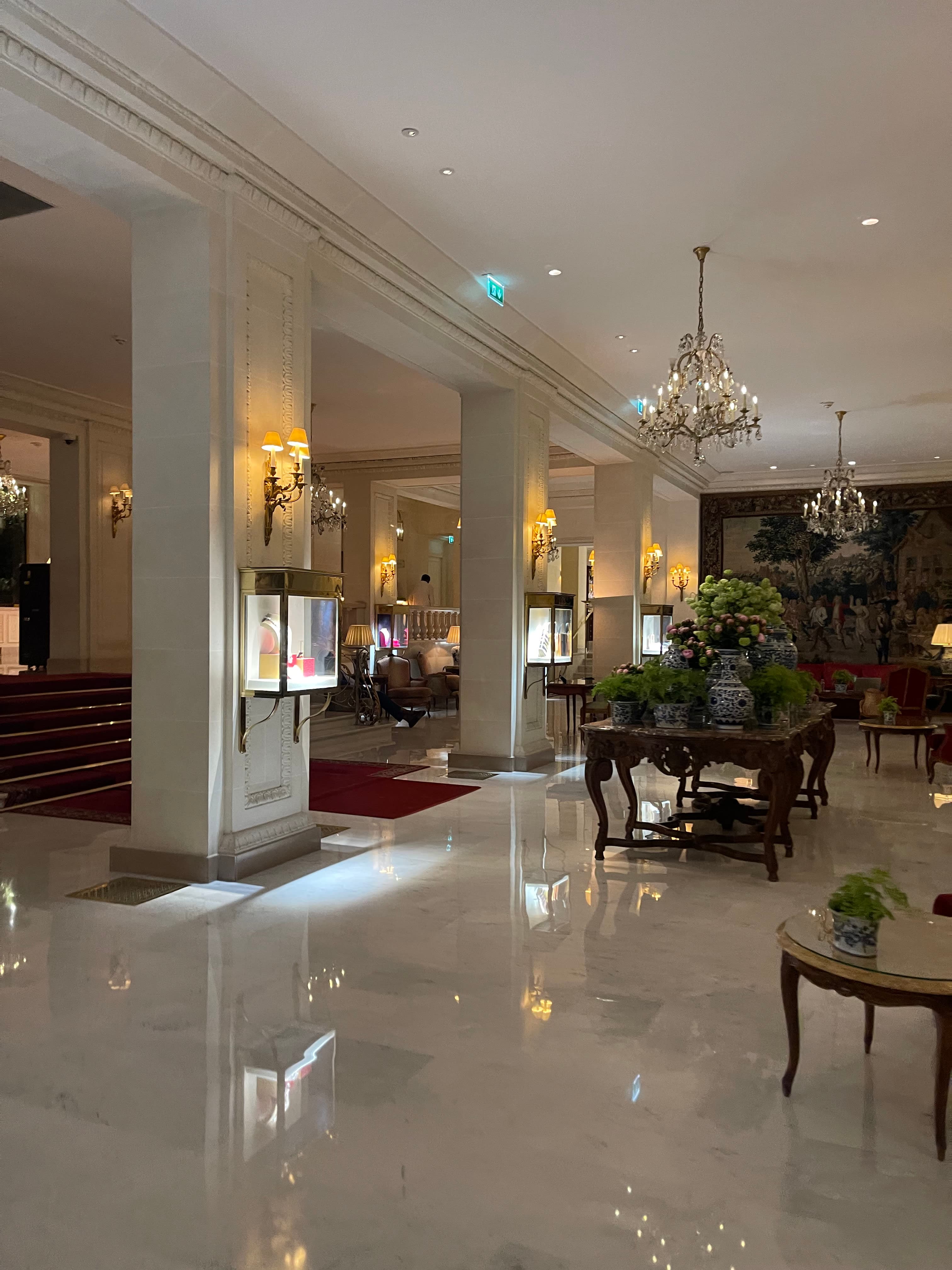 Picture of a polished empty hotel lobby with white marble floors and chandeliers