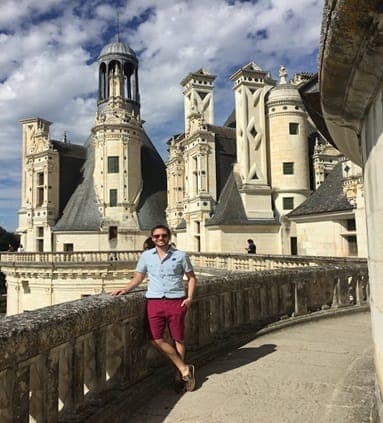 Picture of Kenny in red shorts and sunglasses on a terrace at Château de Chambord on a sunny day