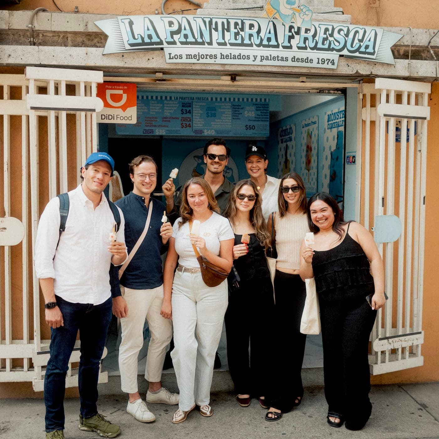 people walk on a boardwalk flanked by palm trees