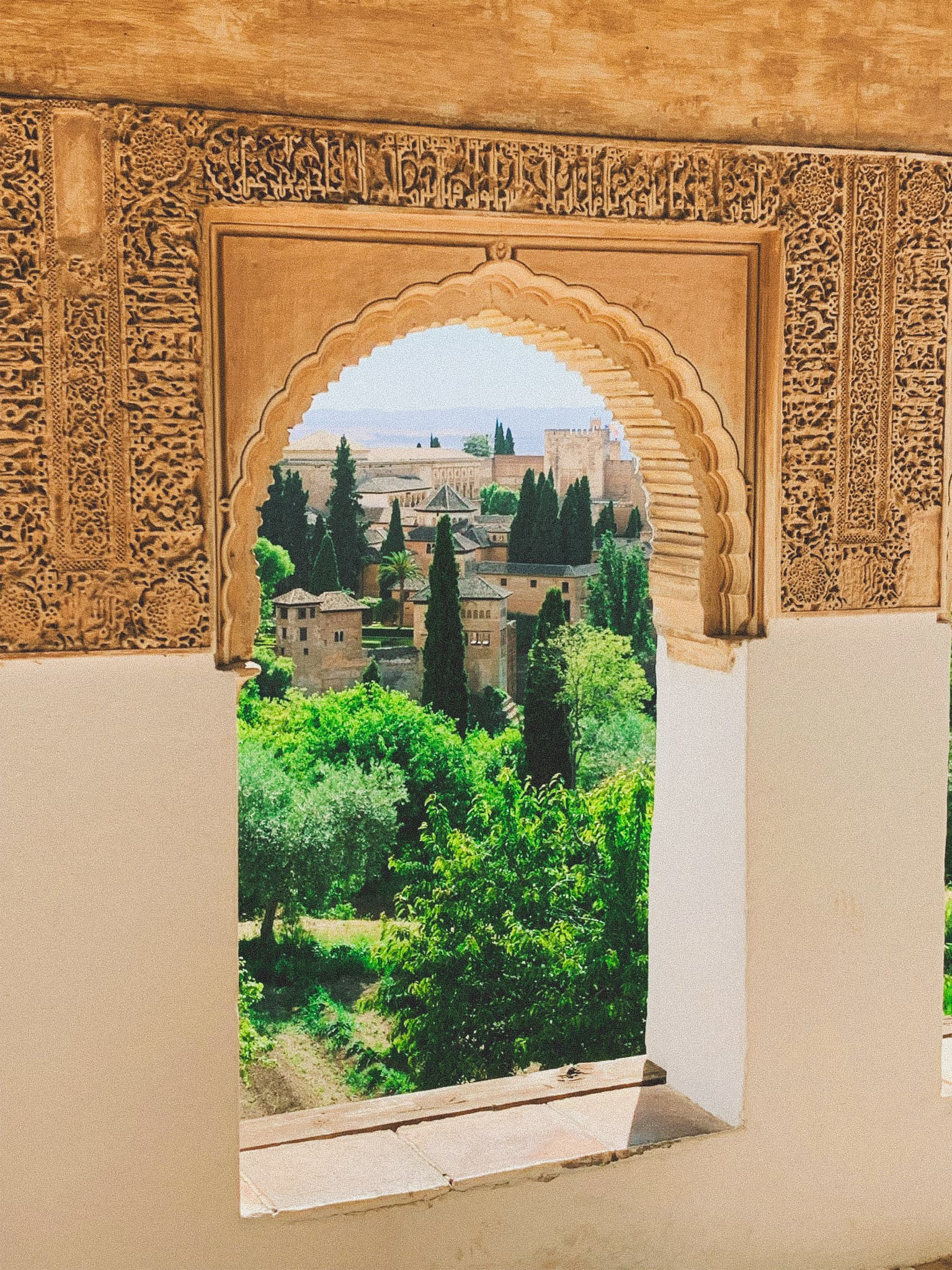 View of a Tuscan countryside landscape seen through a window with elaborate carvings on the outside