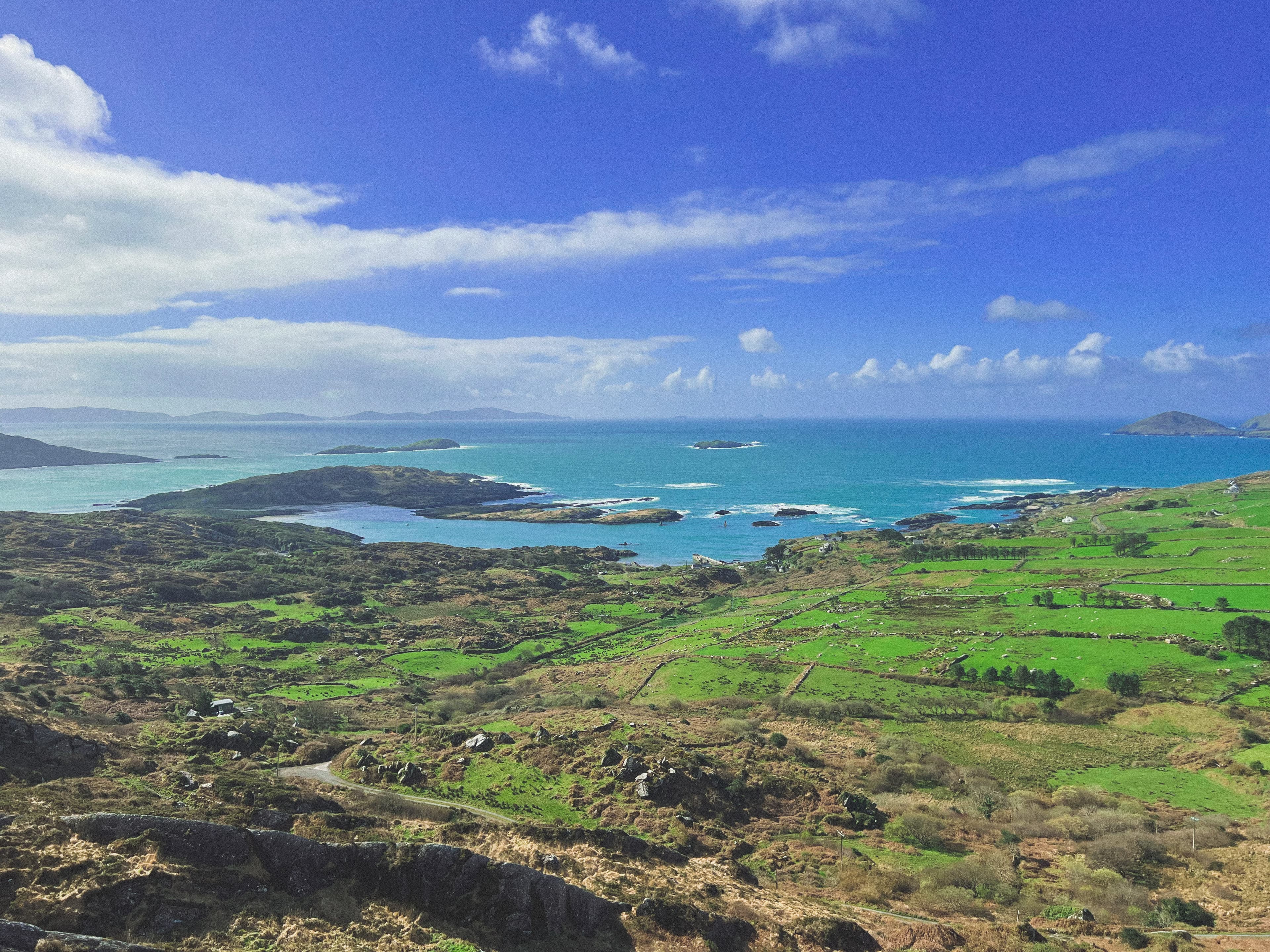 Beautiful aerial view of a coastal area with green fields and rocky cliffs leading out to sea on a sunny day