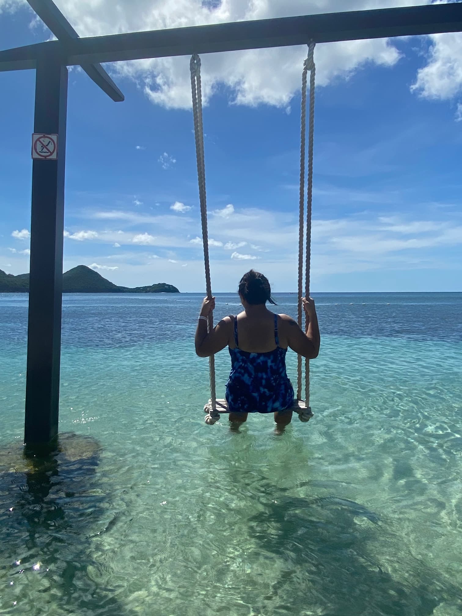 Travel advisor Alyssa on a swing in the ocean with her back to the camera.