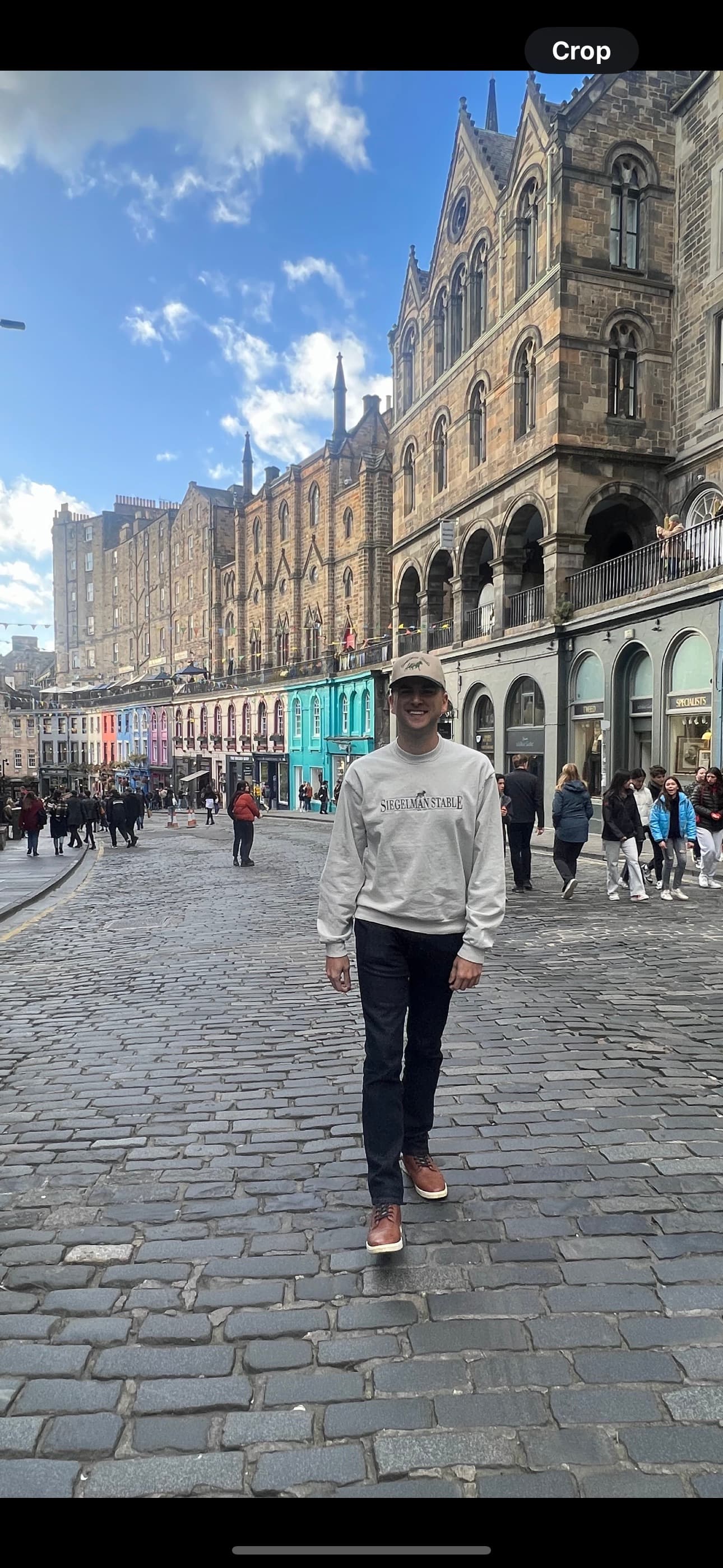 Travel advisor Taylor walking on a stone paved street in front of a row of quaint and colorful buildings.