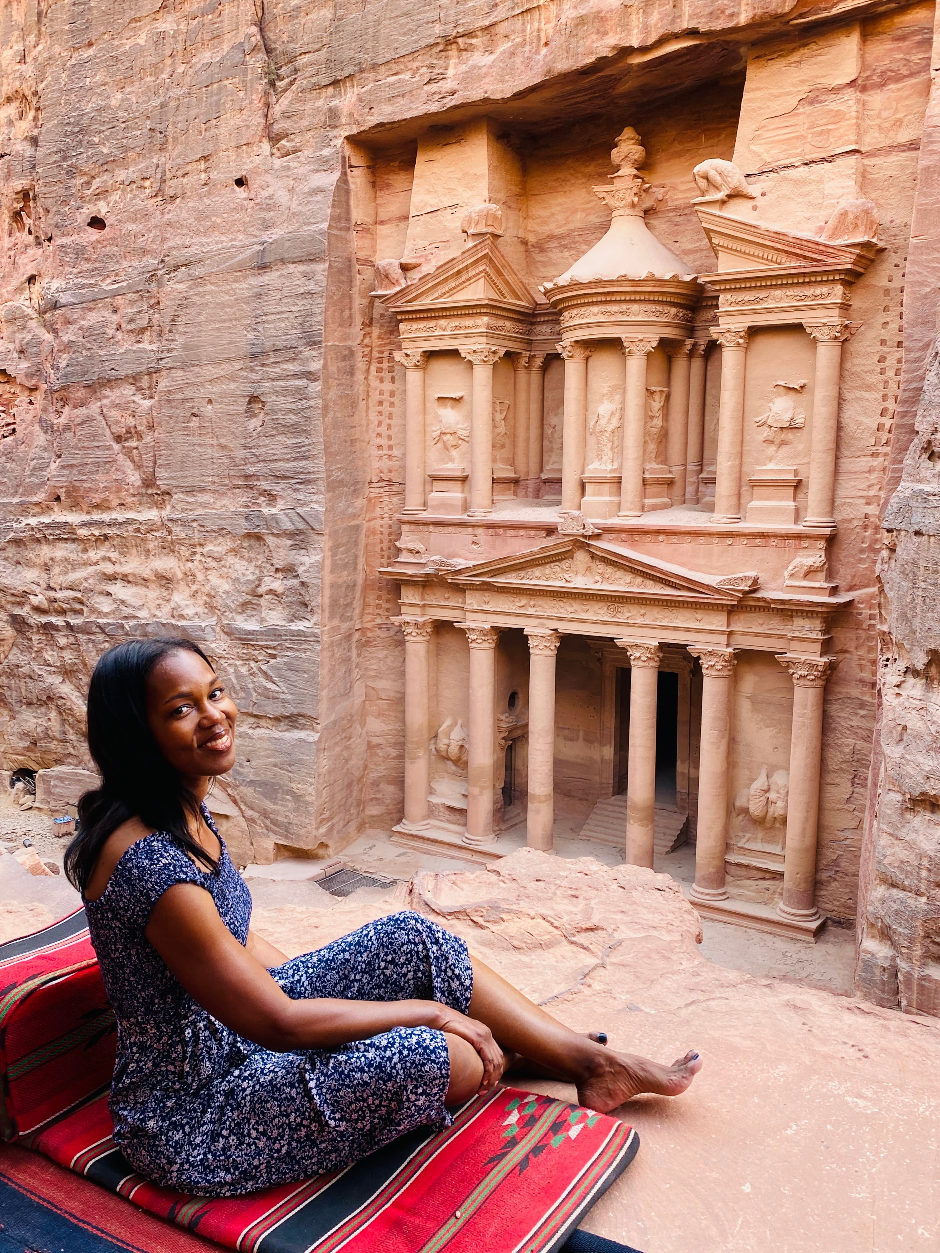 Advisor sitting in a desert setting with a carving of an ancient ruin the mountain side on a sunny day.