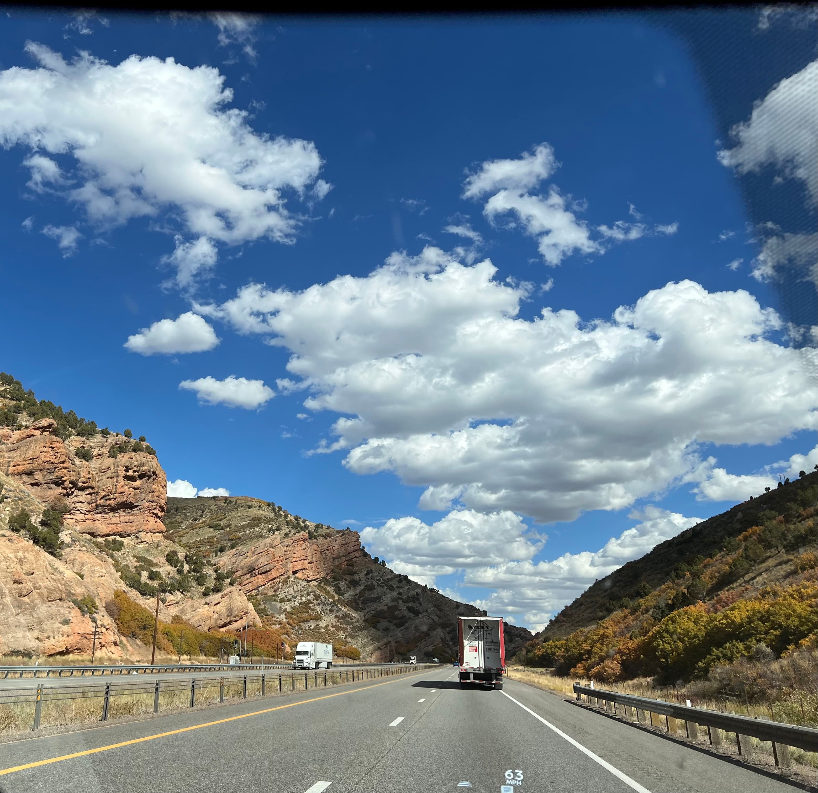 A highway with cars in the distance and clouds in the sky on a sunny day.