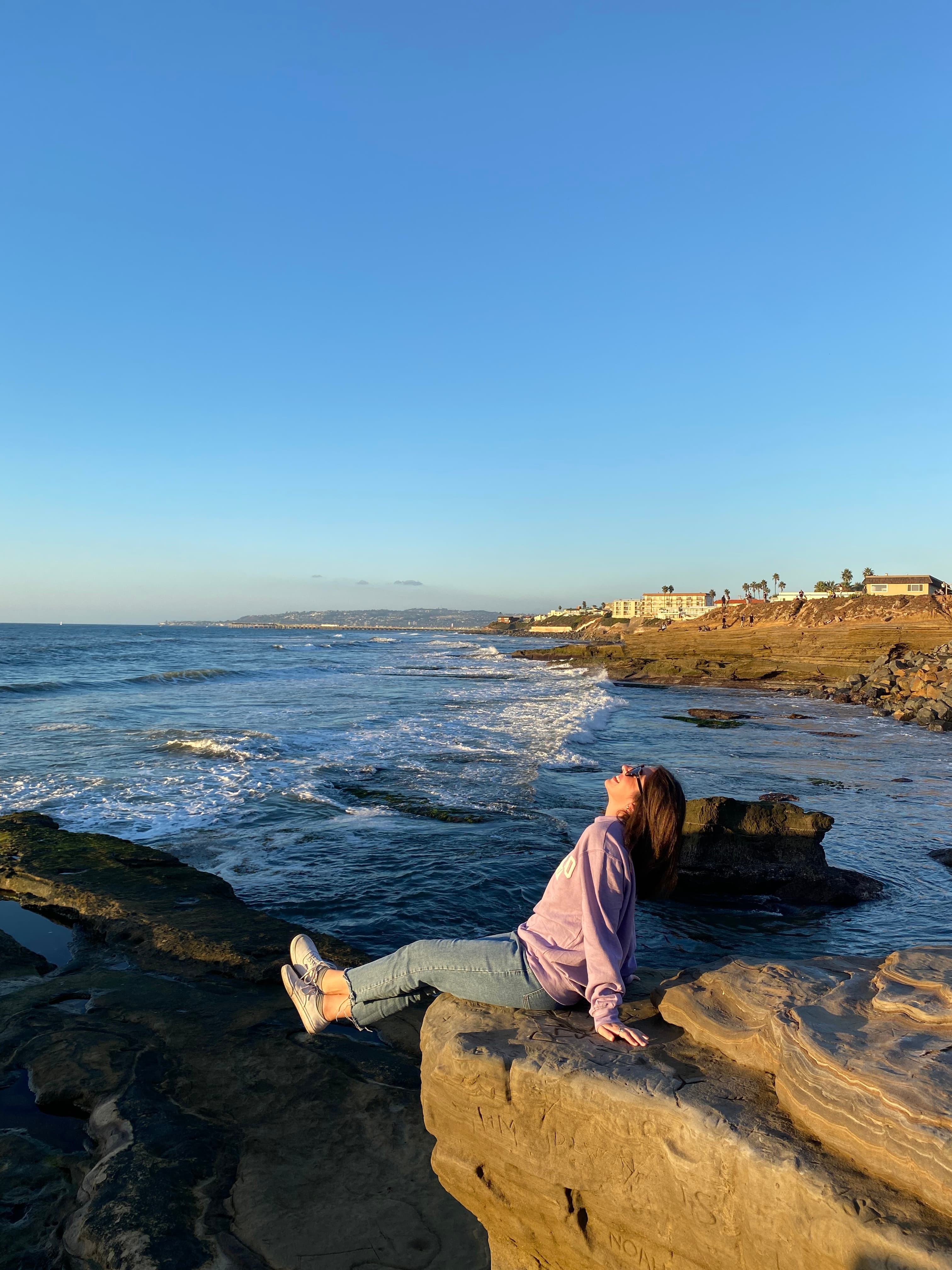 Advisor laying out on rock formations with the ocean in the distance.