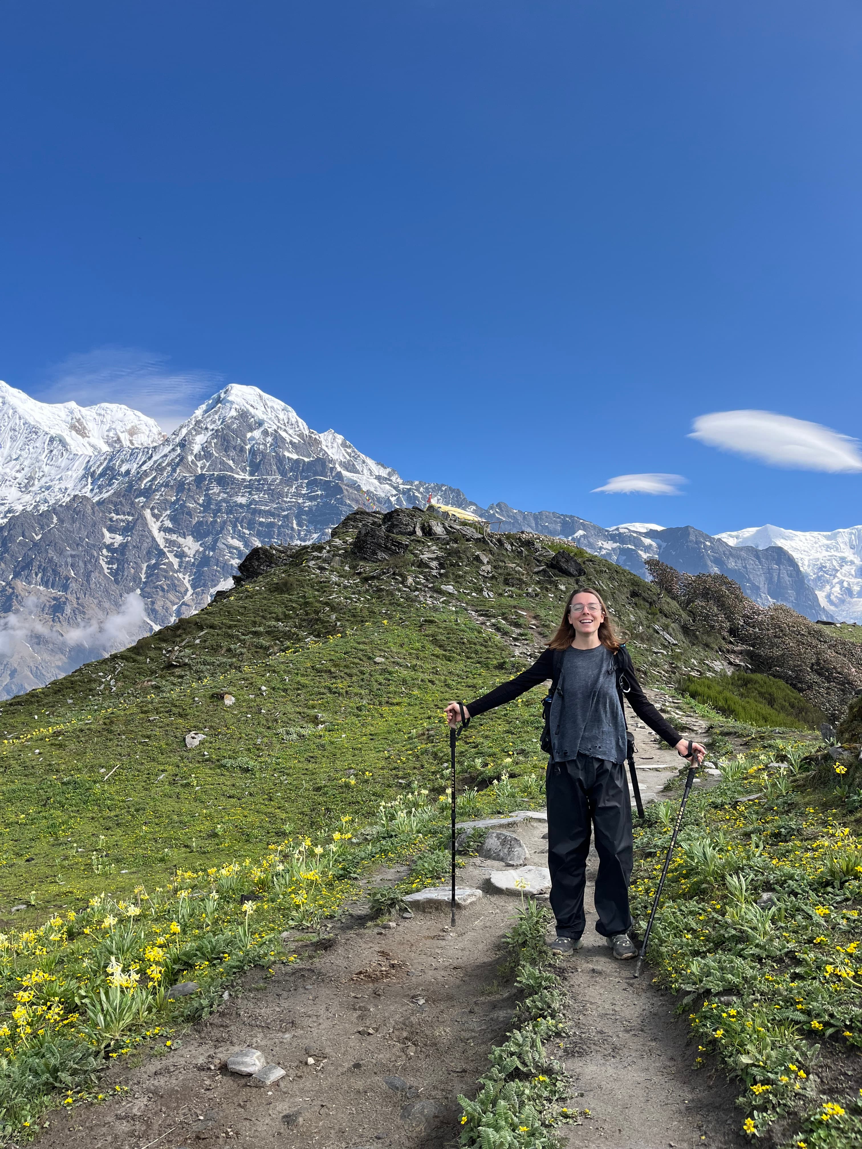 Advisor posing for an image while hiking a mountain range on a sunny day with snow covered mountains in the distance.