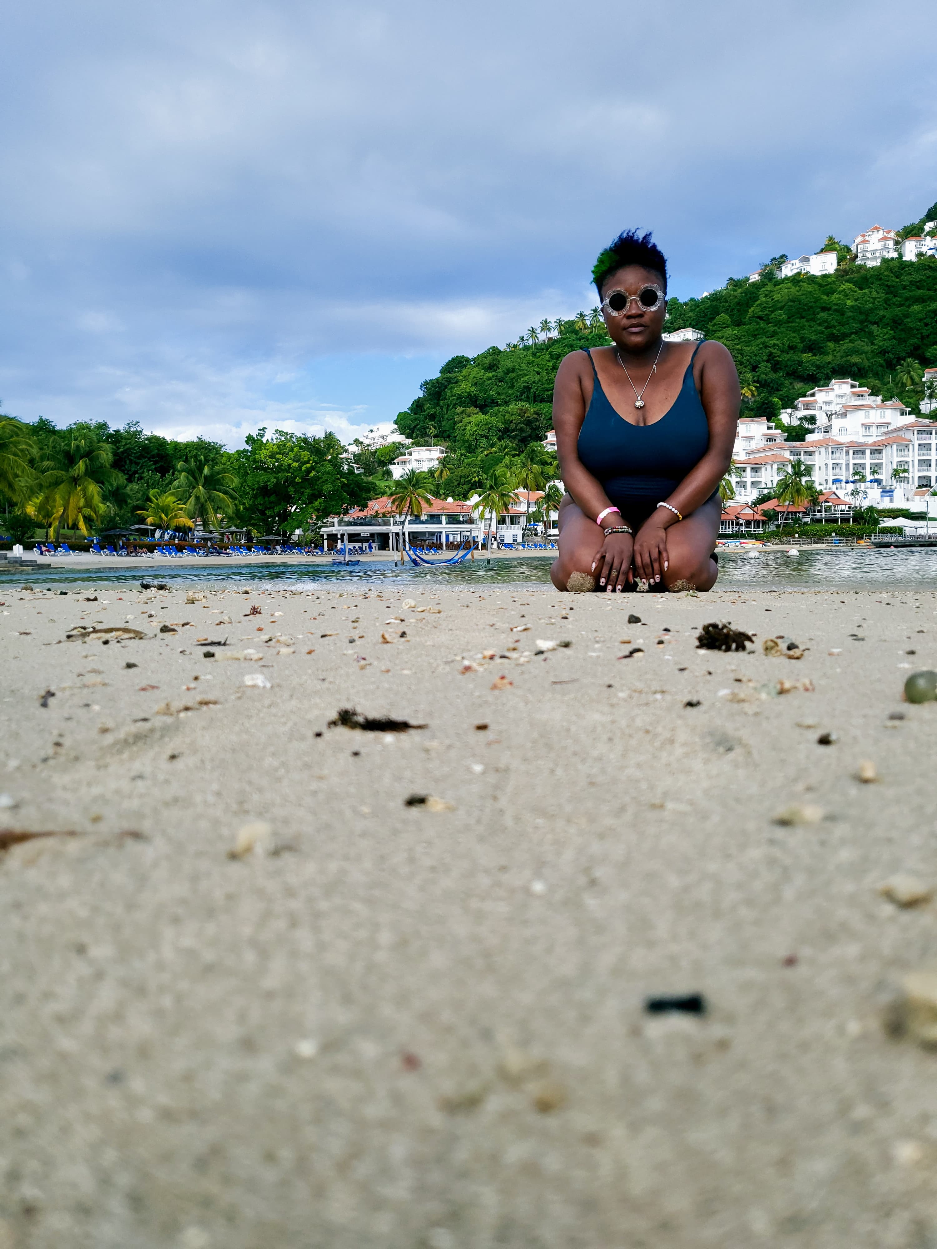 Advisor sitting on the beach in a black swimsuit on a sunny day.