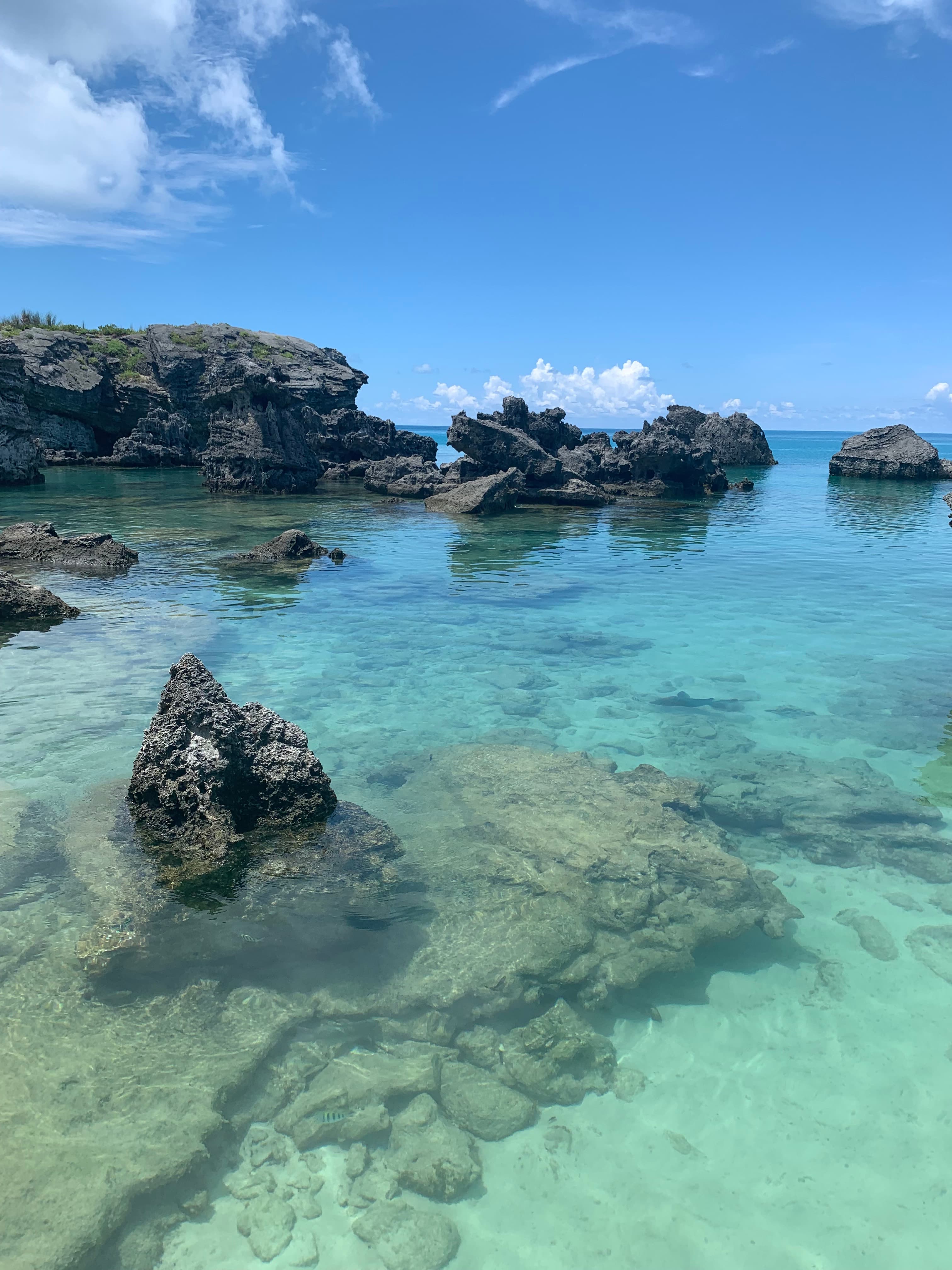 View of a beautiful clear ocean with several underwater rock formations on a sunny day