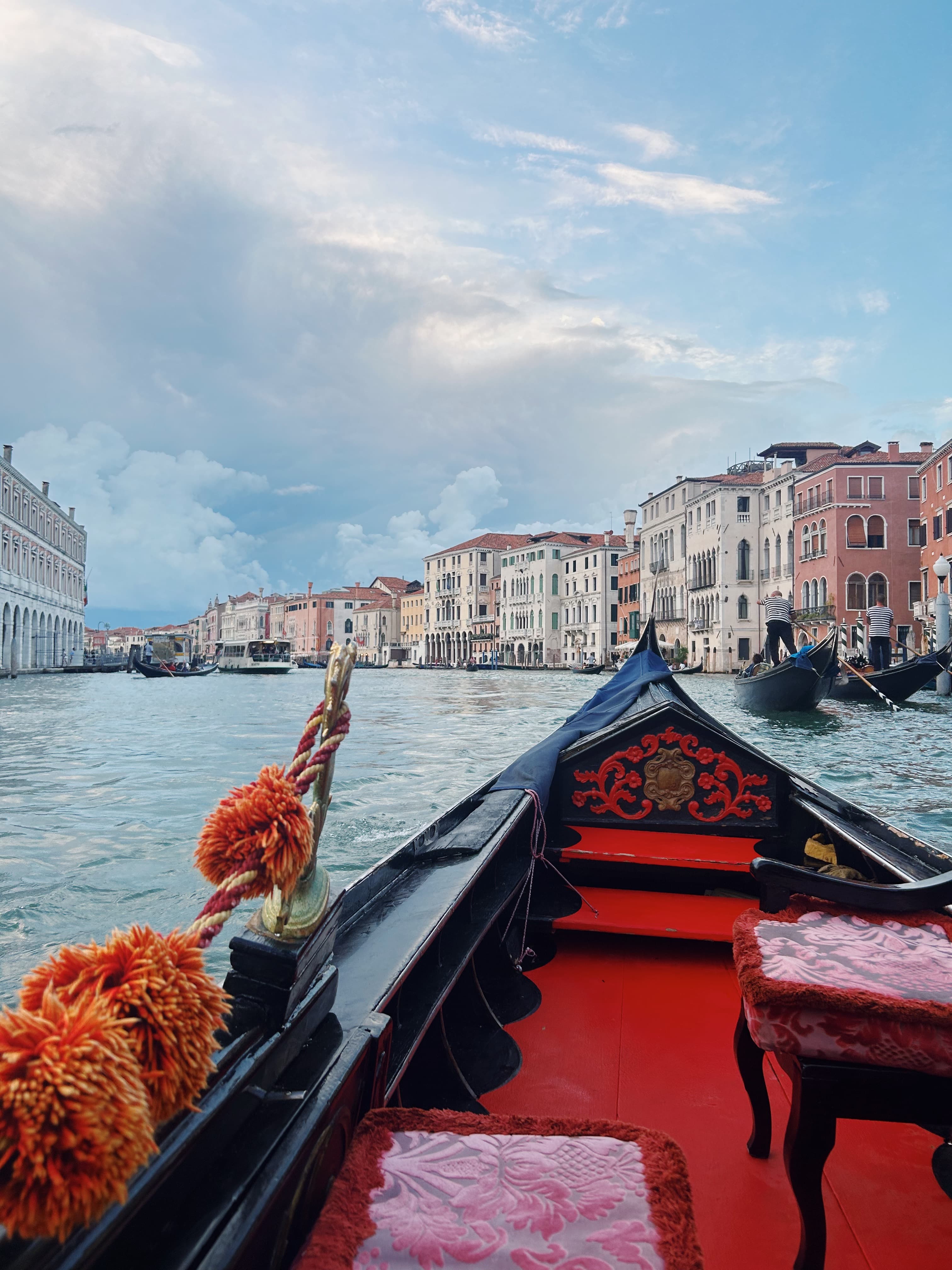 View of the front of a gondola on a canal in Venice, Italy with buildings visible on the water