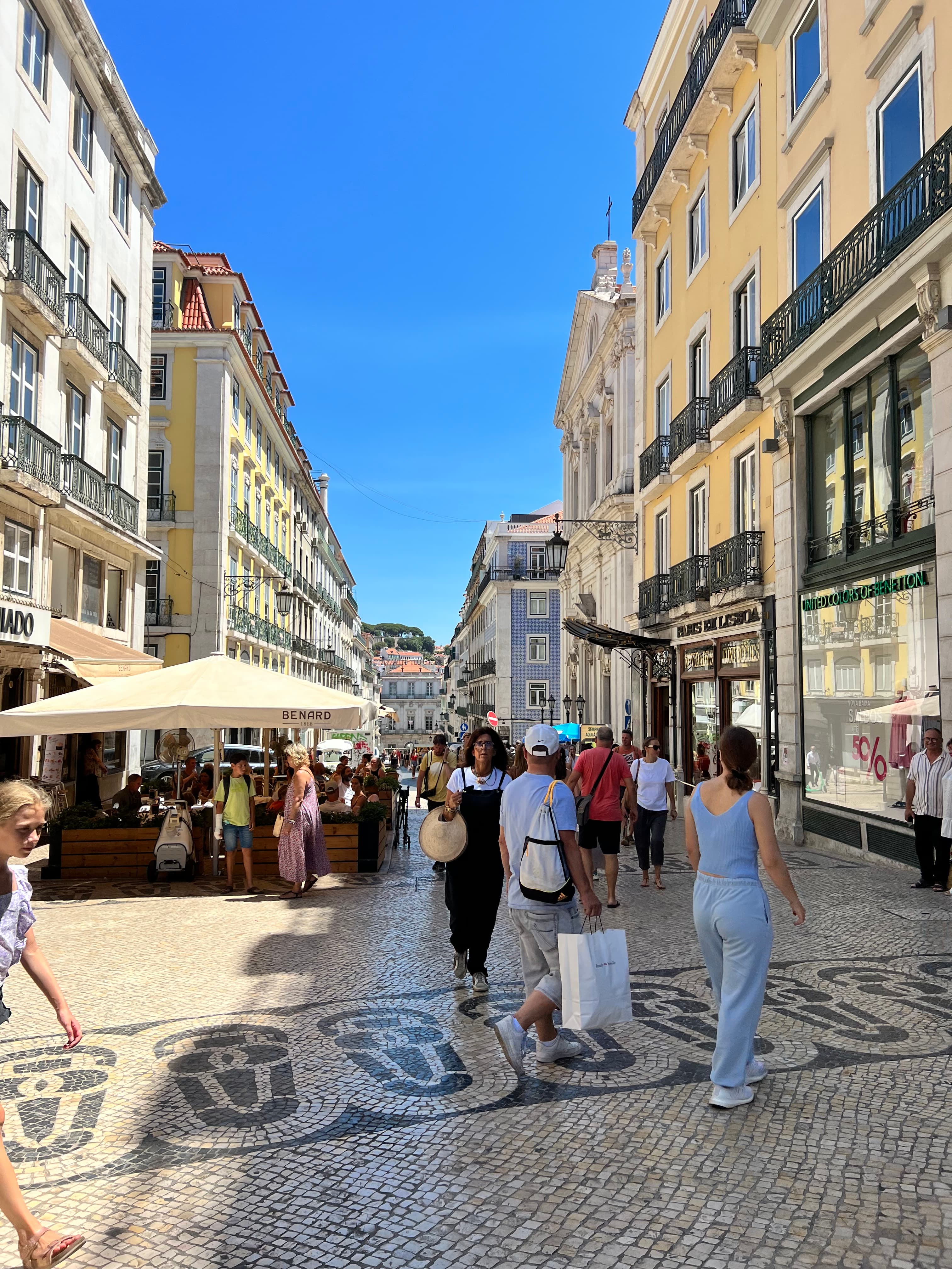 View of a tiled city street with many pedestrians on a sunny day