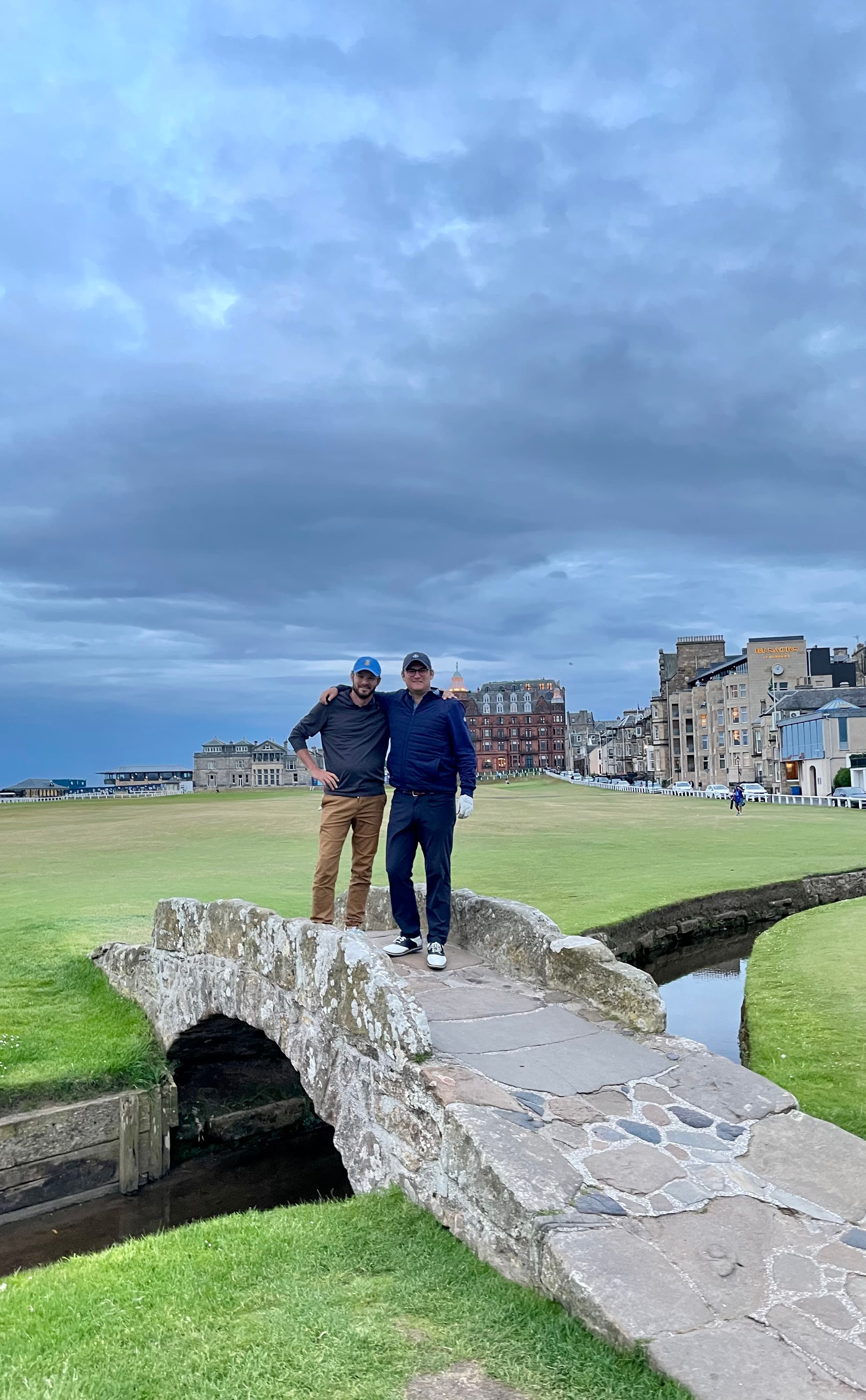 Advisor posing on a golf course with a friend on a cloudy day.