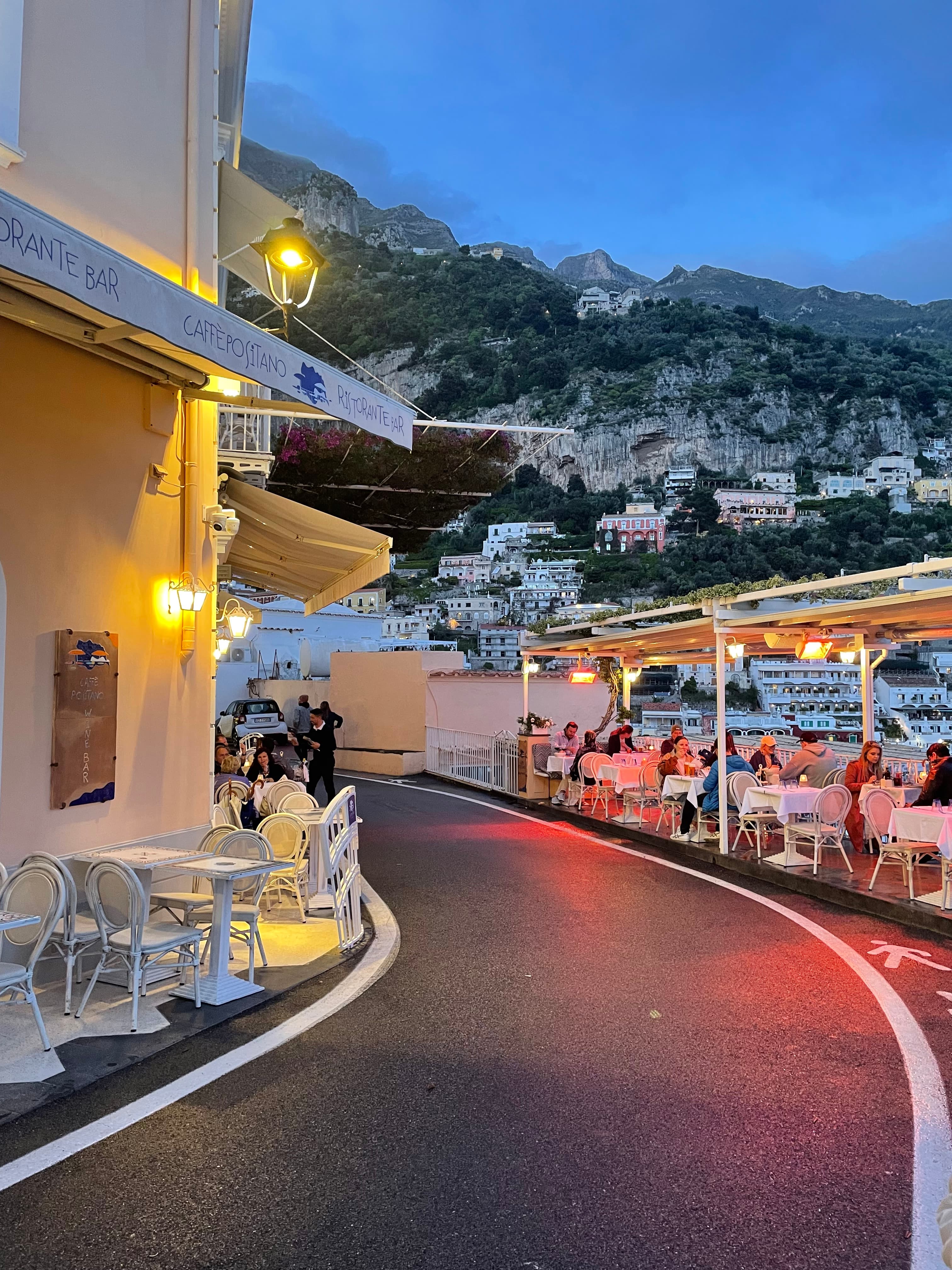 Pretty view of a street winding through white buildings and outdoor patio areas at twilight