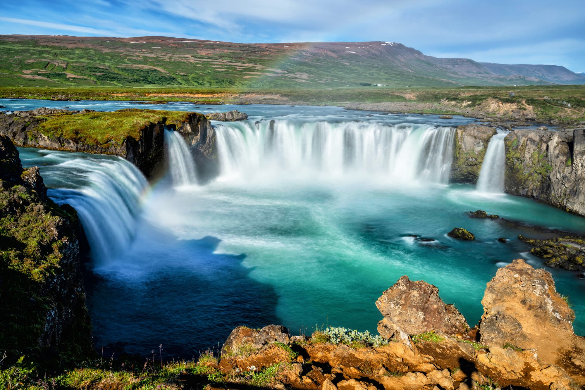 Beautiful aerial view of a massive waterfall surrounded by mountains on a sunny day