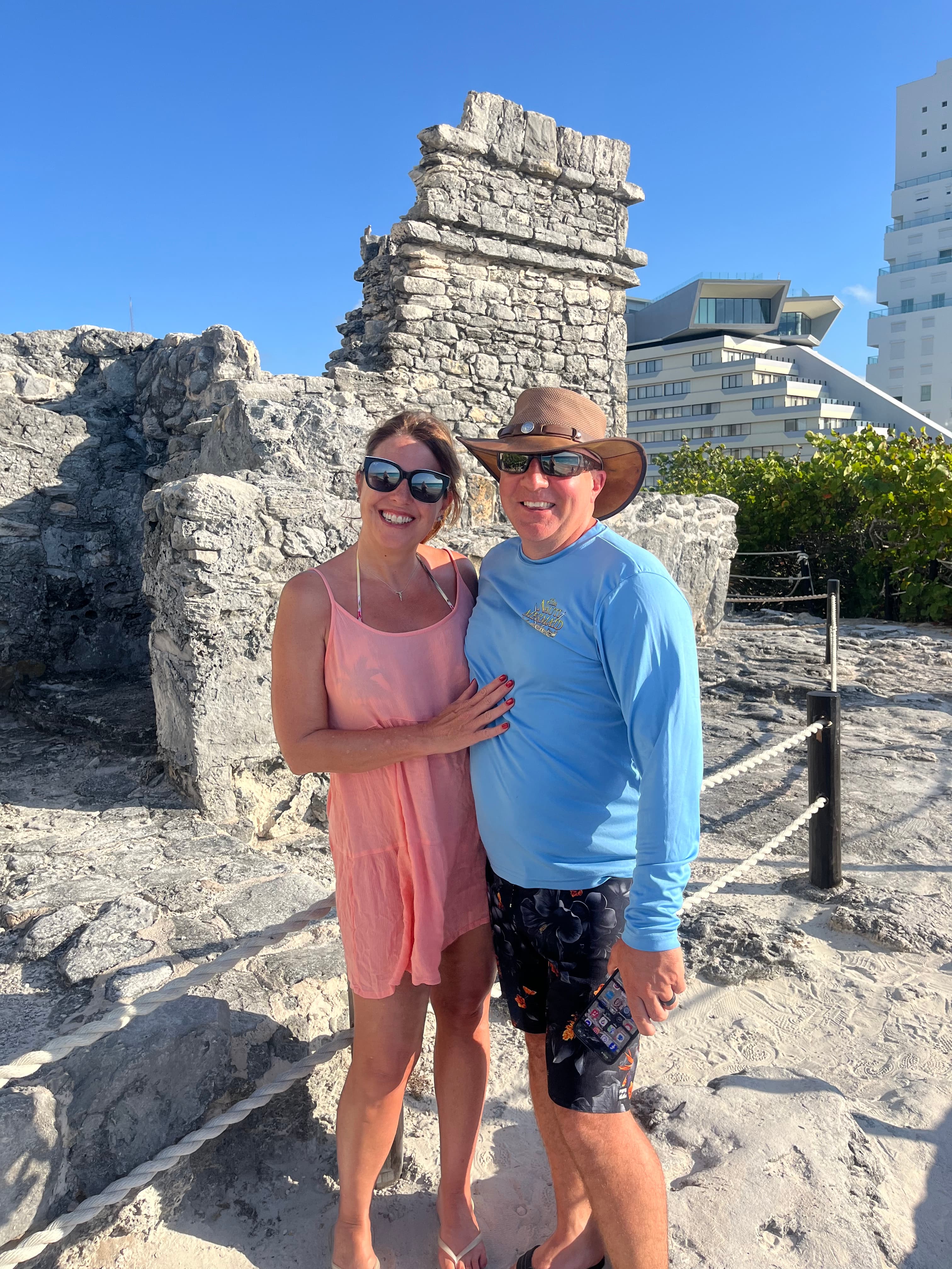 Couple standing in front of ruins on a sunny day.