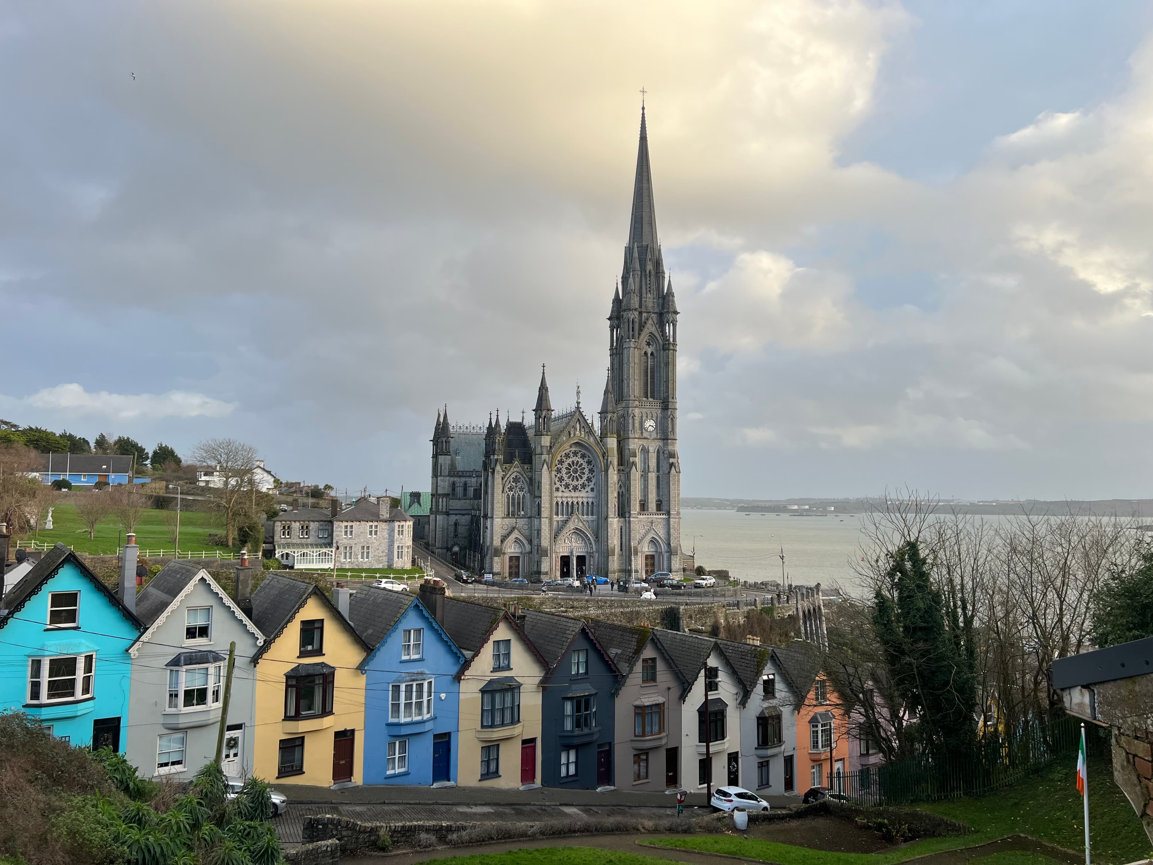 View of colorful buildings lined up in front of a beautiful old cathedral with the sea in the distance