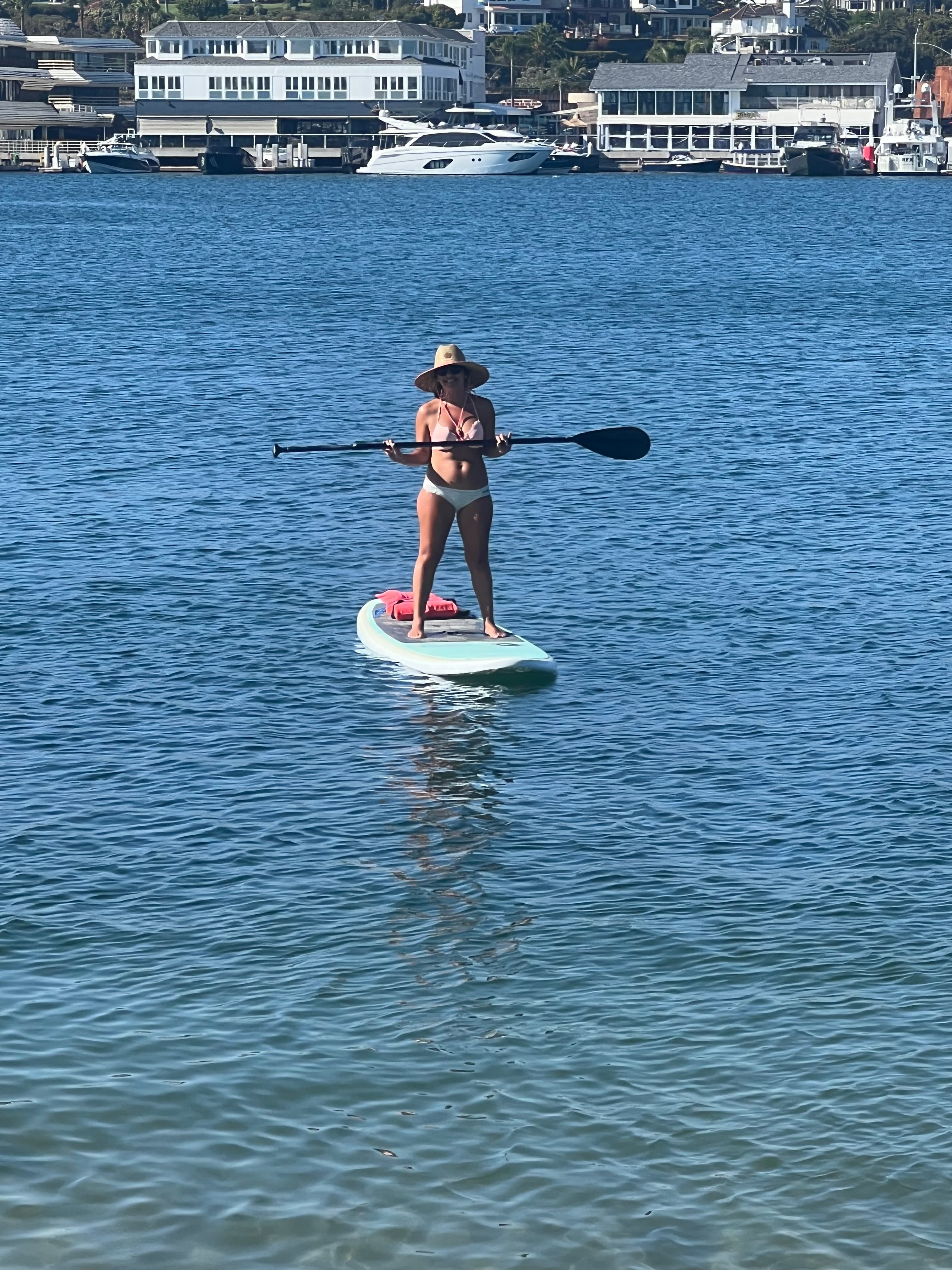Bridget standing on a paddle board at sea with an oar in hand