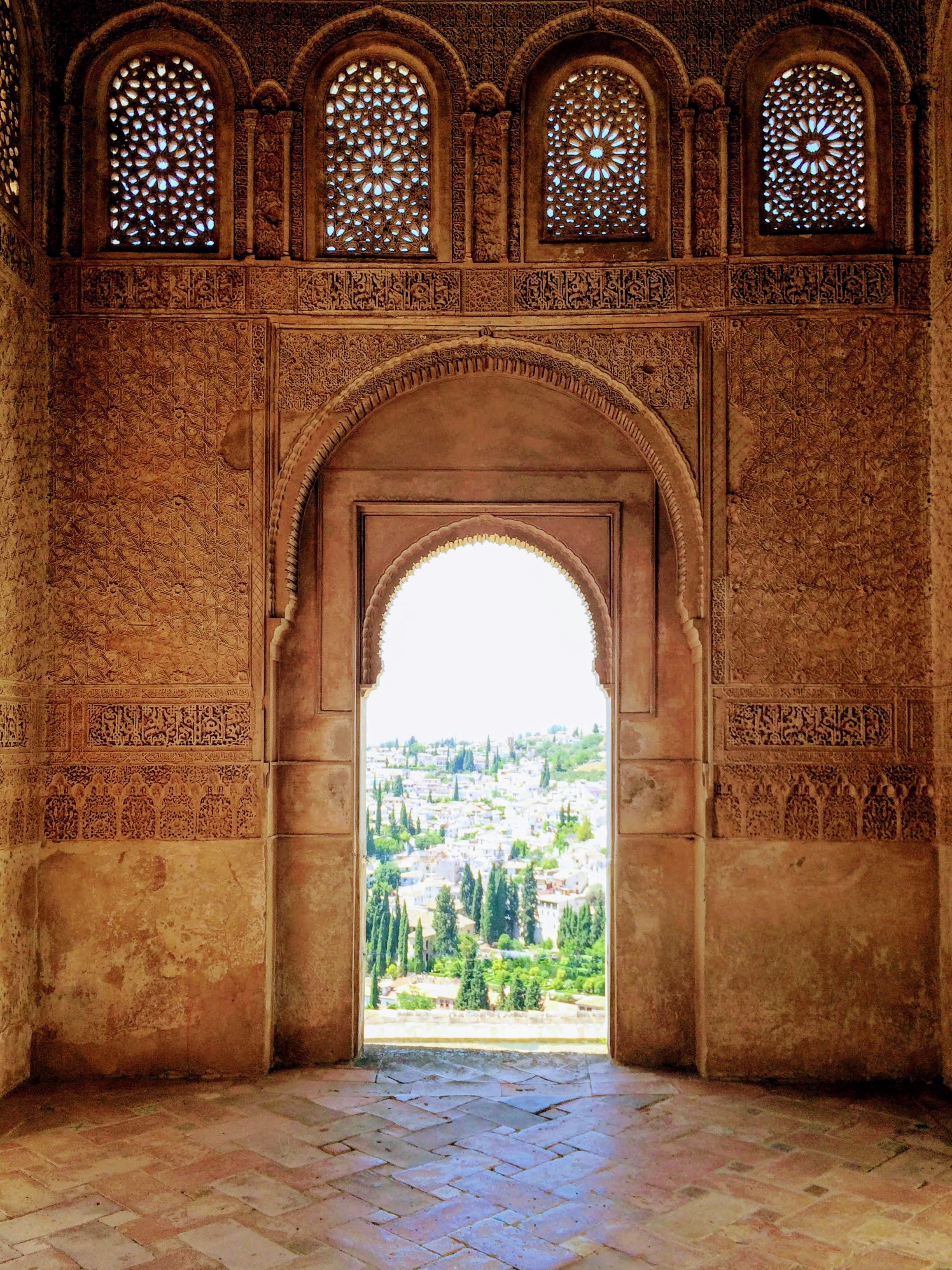 Image of an arched doorway leading to outside greenery on a a sunny day.