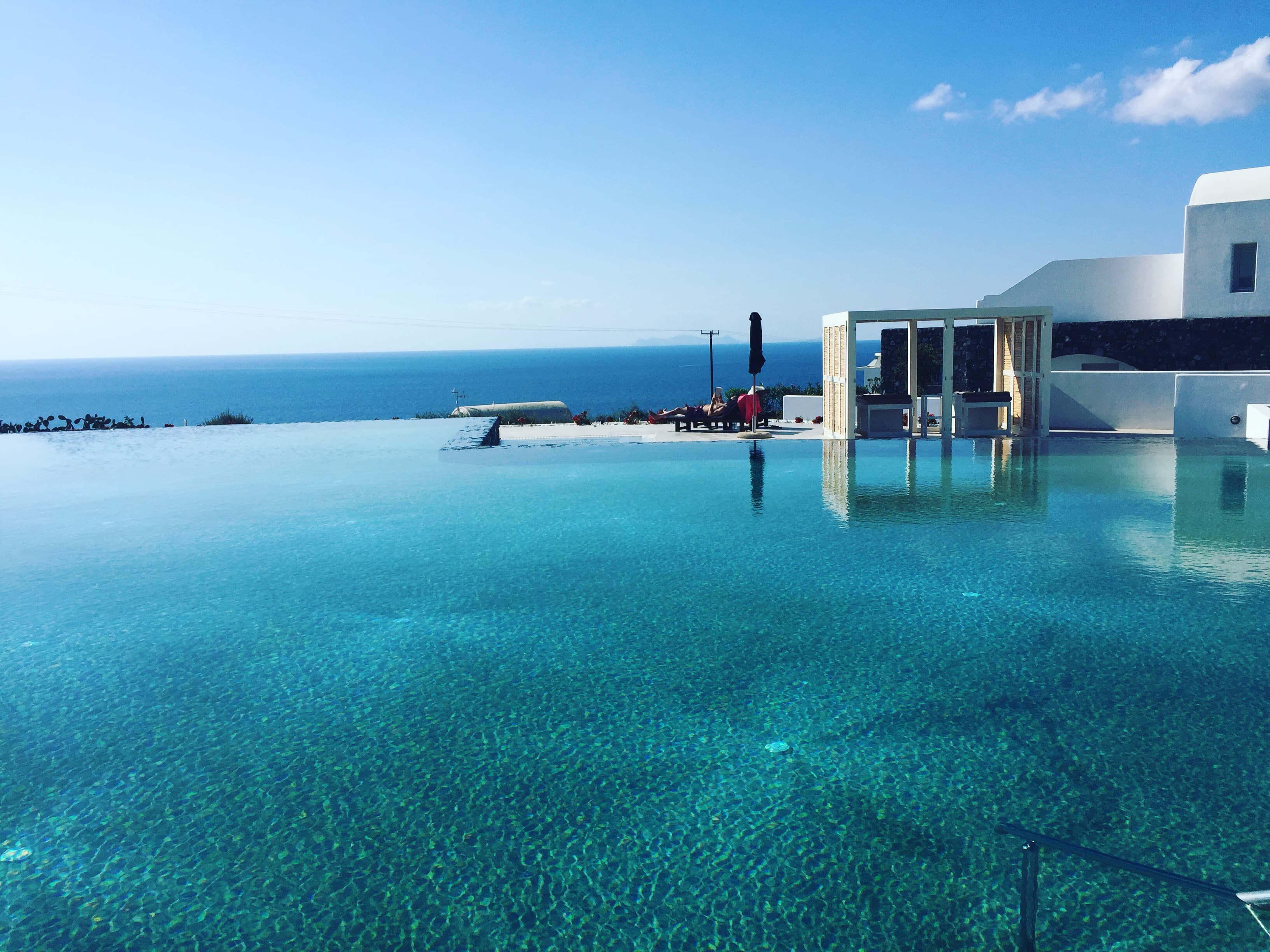 Beautiful view of a large empty infinity pool at a resort overlooking the ocean on a sunny day