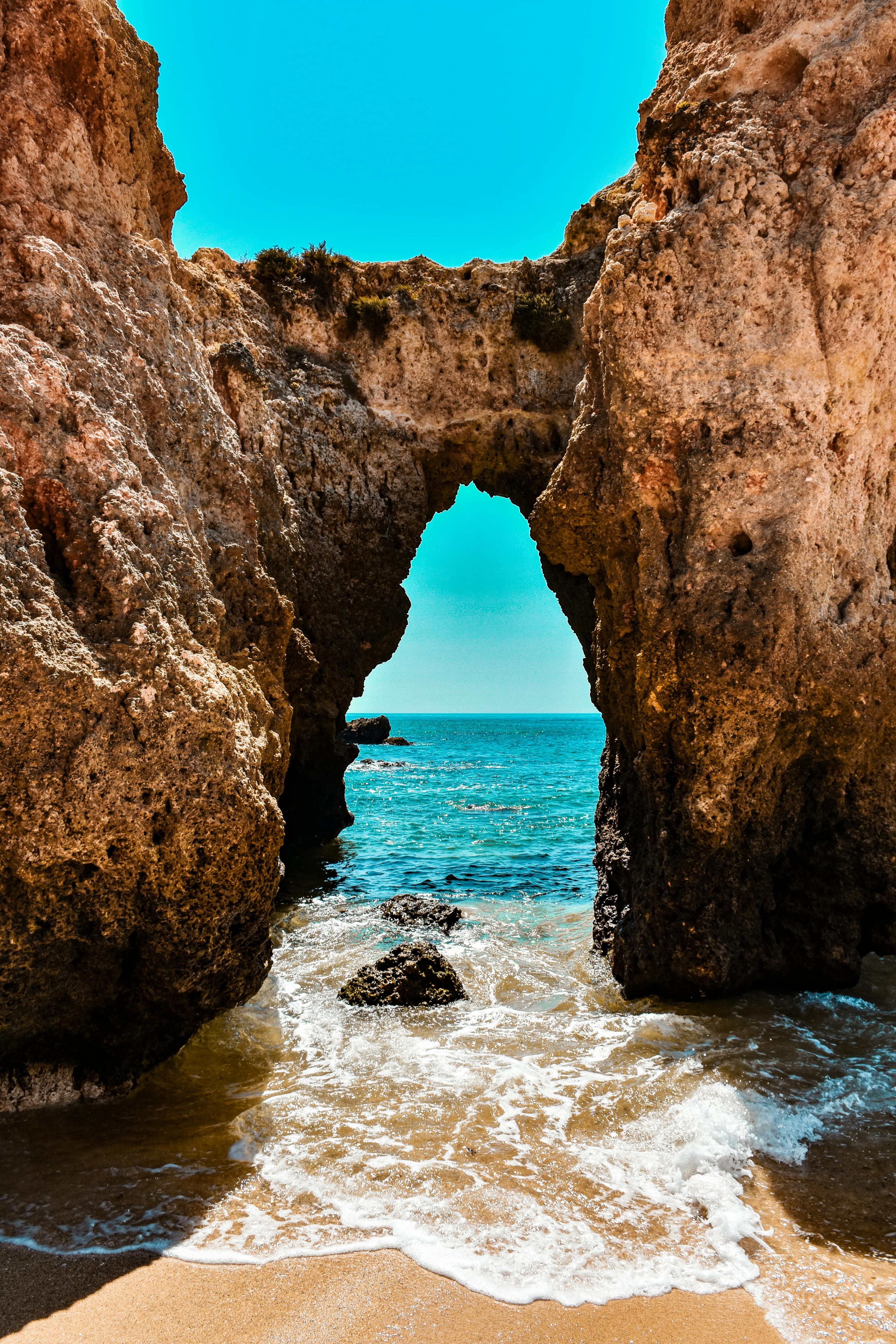 An ocean view with overhead cliff on a sunny day.