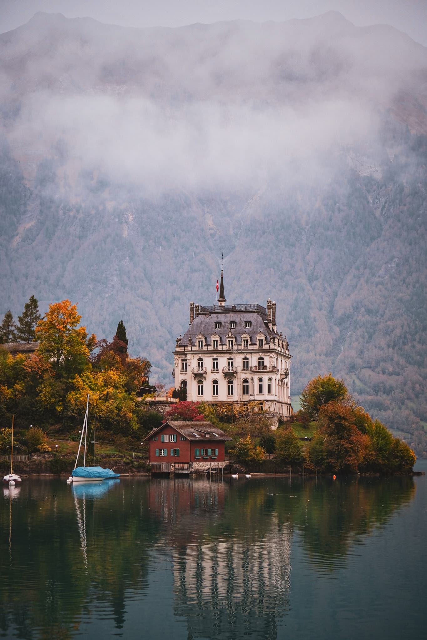 A traditional building over the water with mountains in the back.
