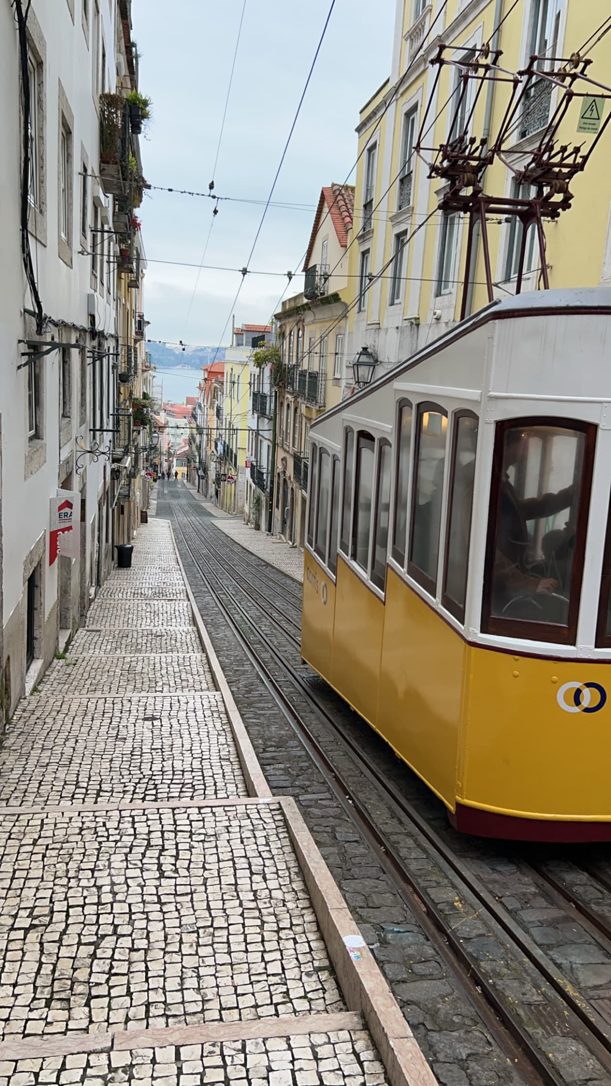 View of a street in Lisbon with the famous yellow tram on a cloudy day