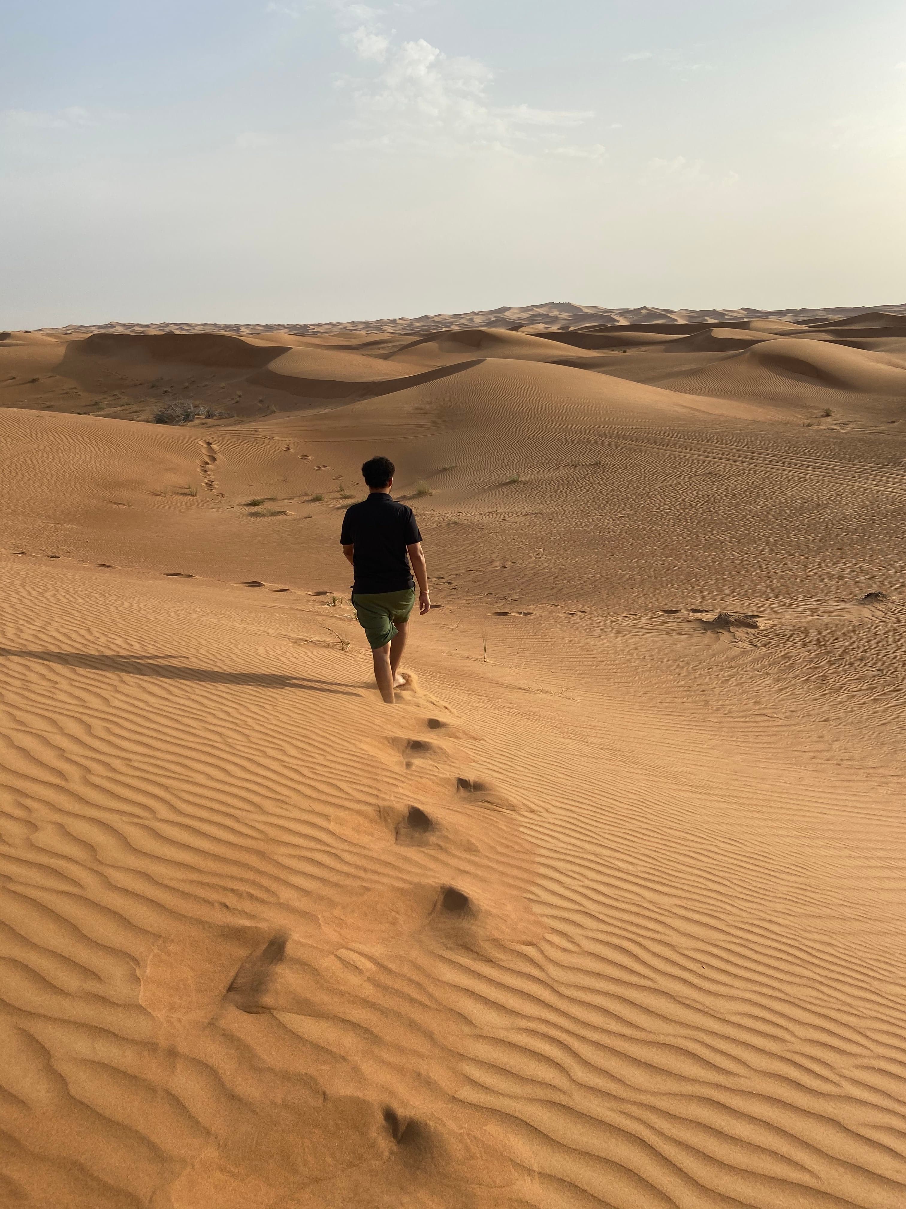 Advisor walking through an empty desert landscape towards the horizon leaving footsteps in the sand