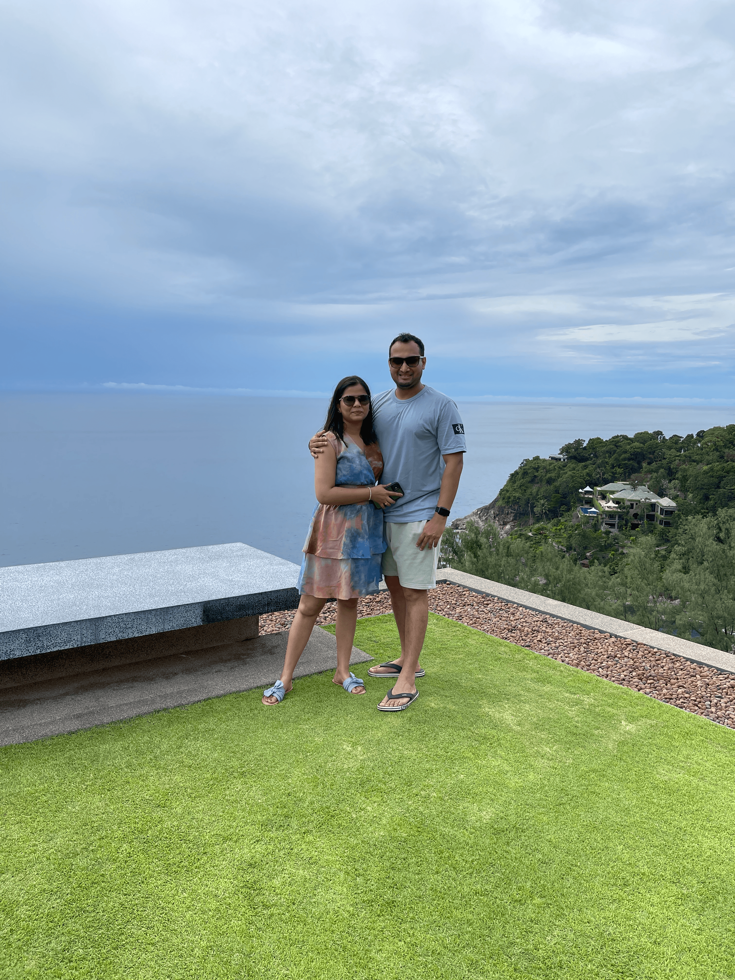 Advisor posing with his arm around a woman on a grassy area overlooking the sea on a cloudy day