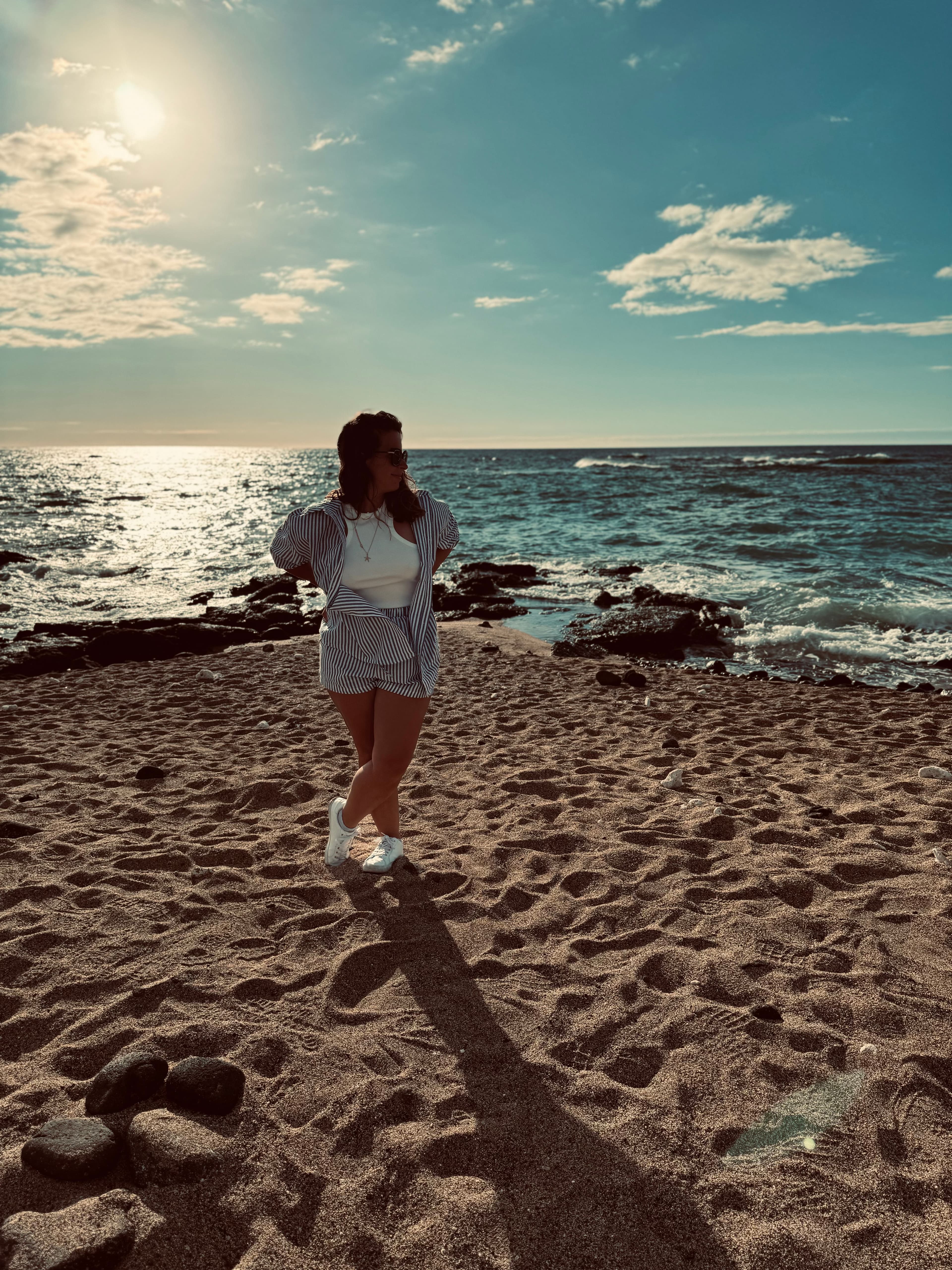 Sharon posing with her hands on her hips on the beach under sunny skies