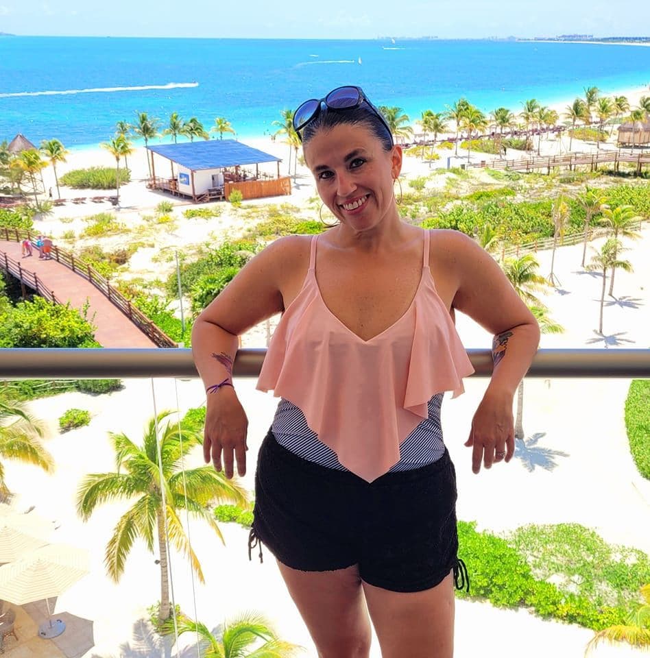 Advisor posing in front of beach lined with palm trees.