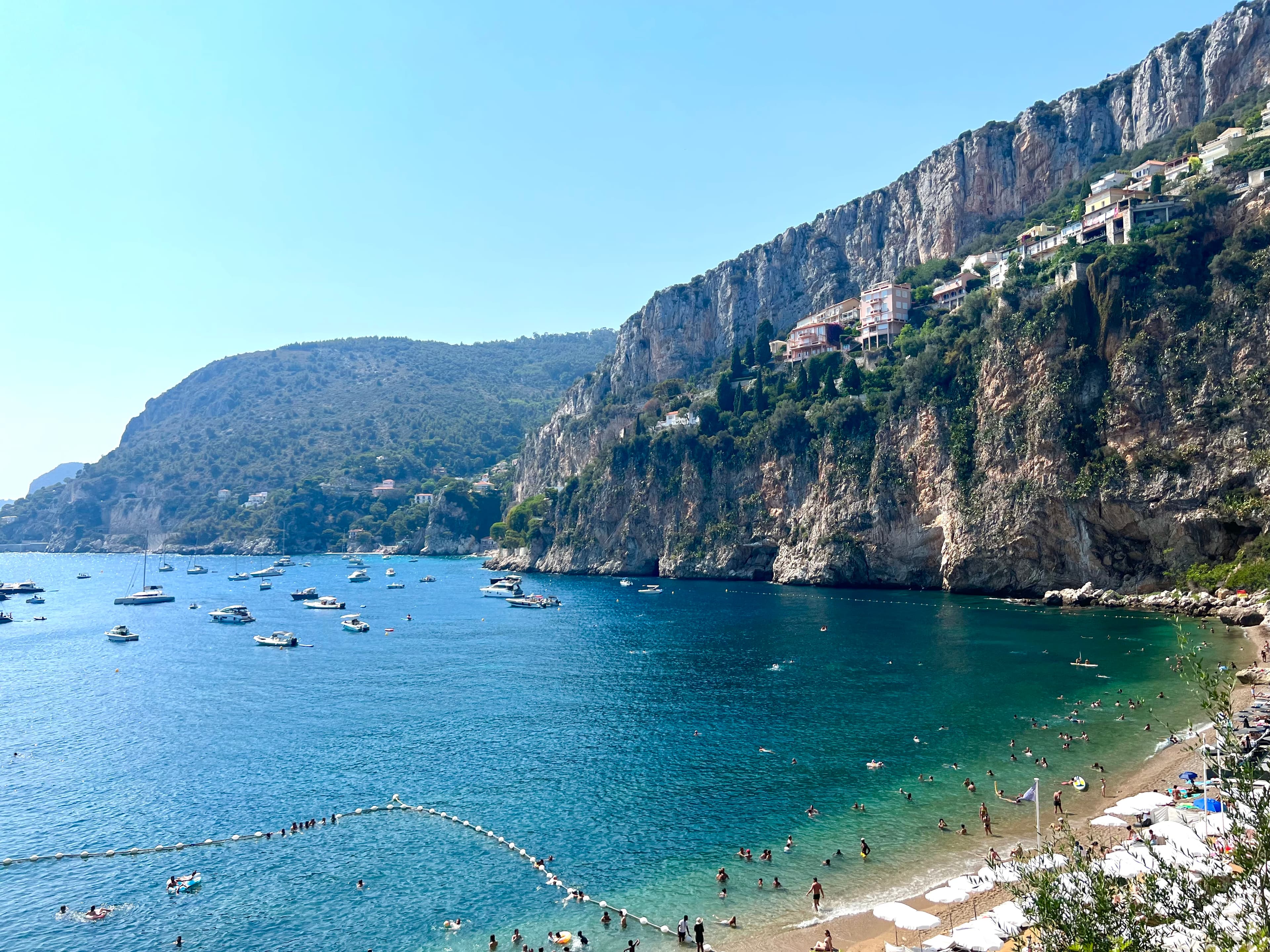 Beautiful view of a coastline with steep cliffs and many small boats offshore on a sunny day