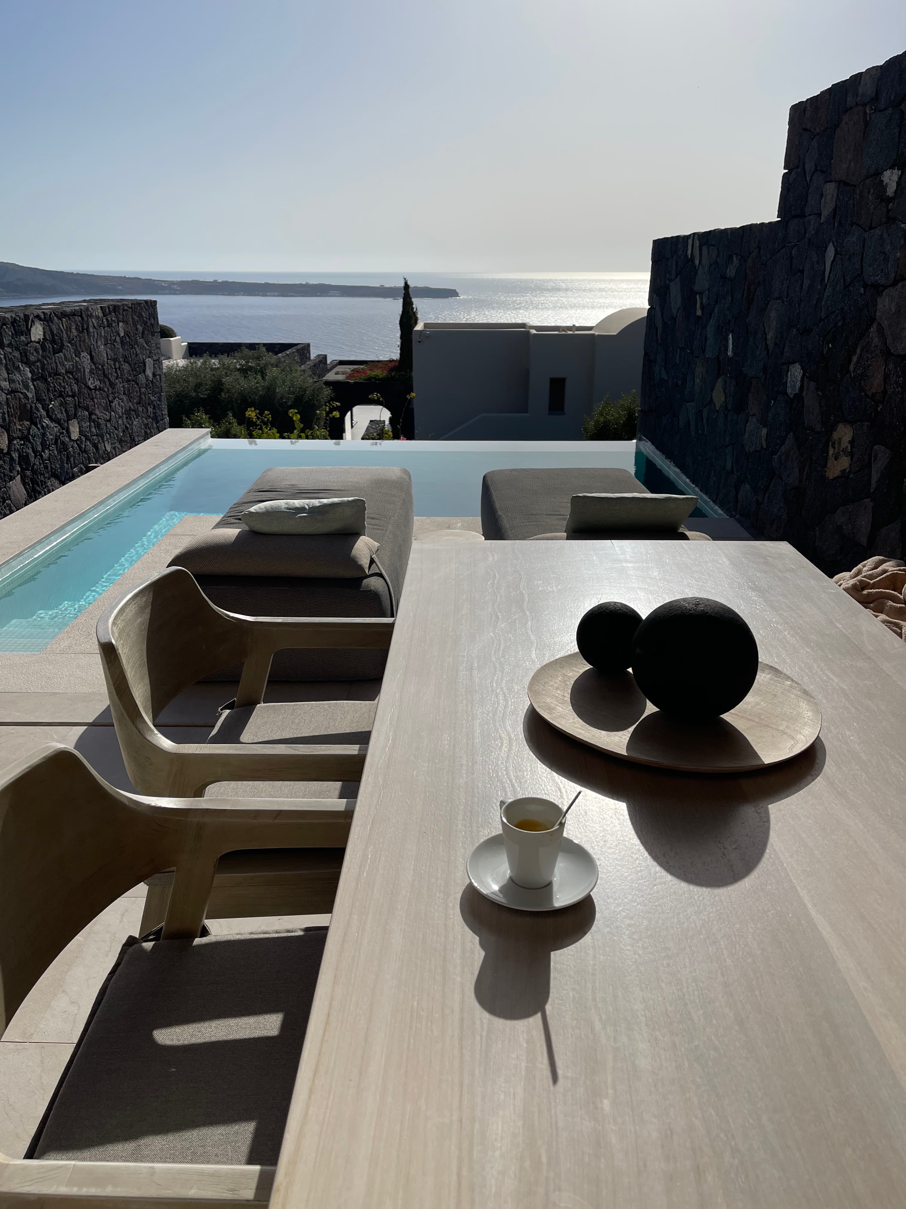 View of a table and chairs poolside during the daytime.