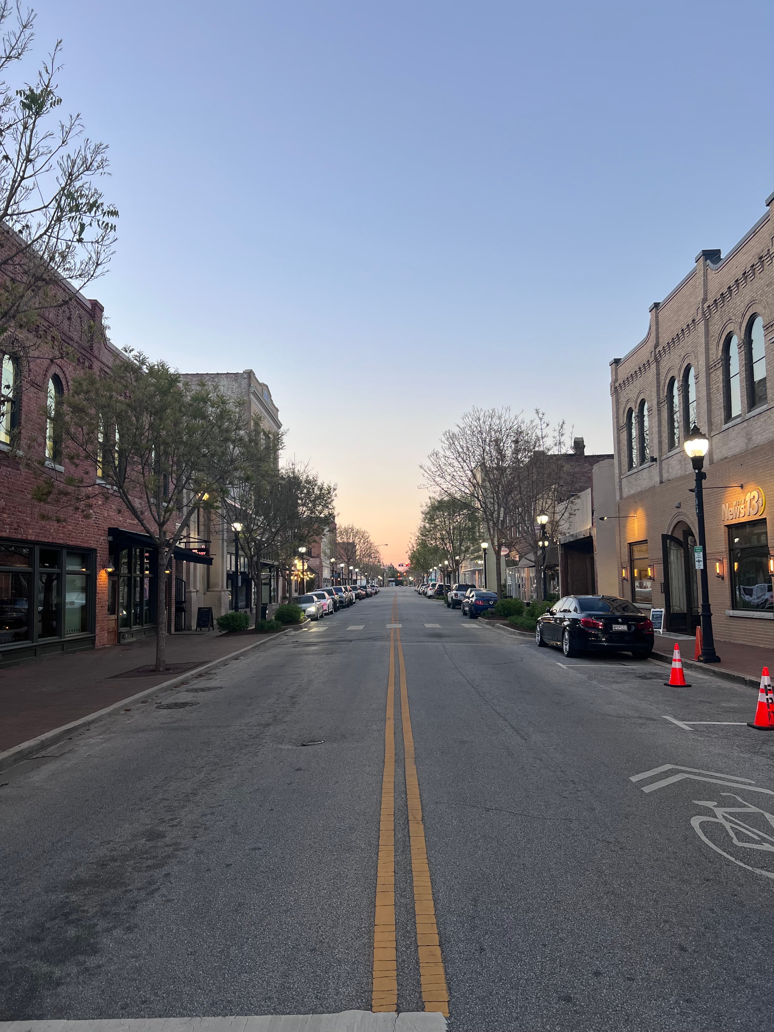 Quaint buildings line the street on a quiet block at dusk.