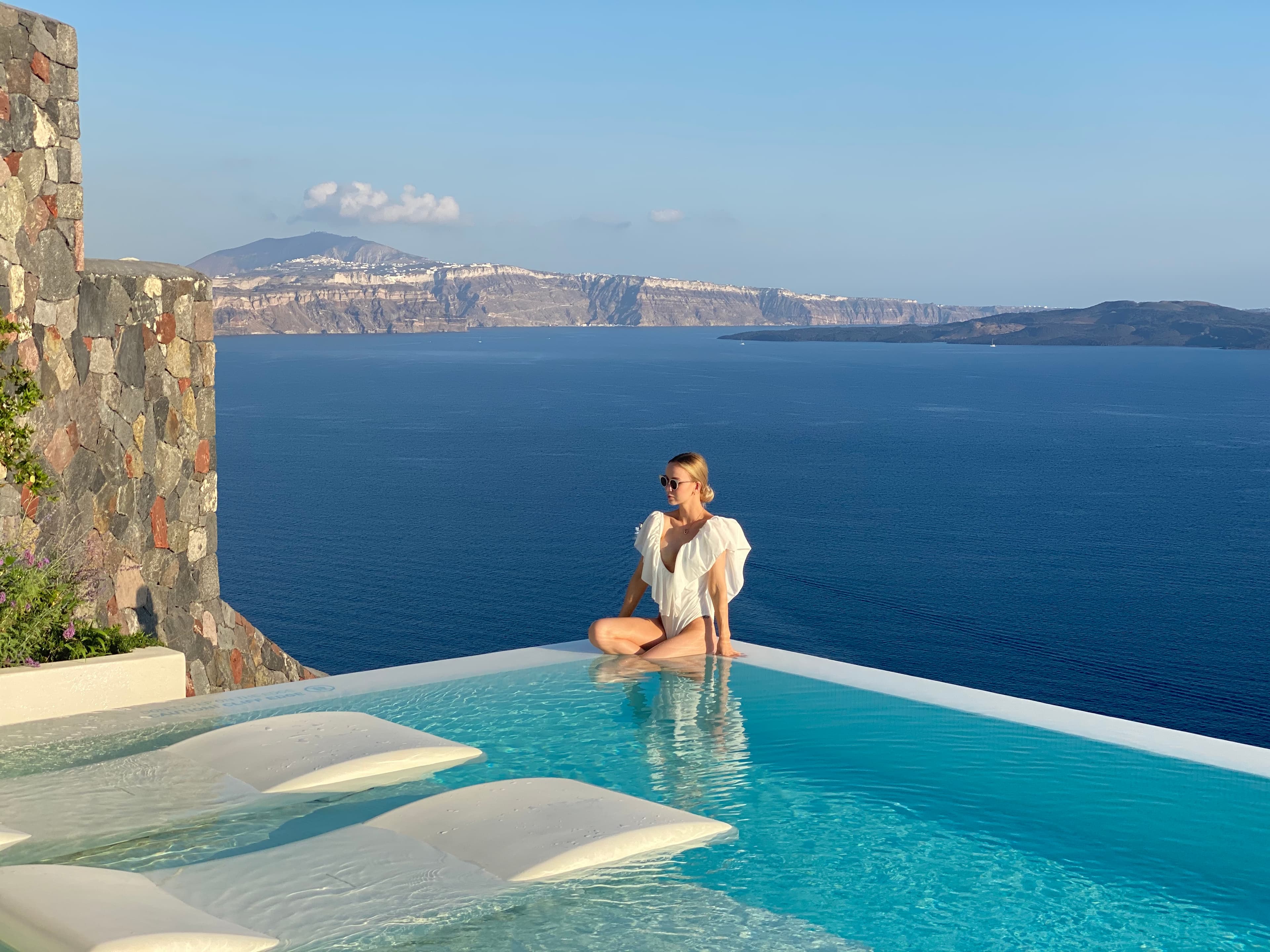Advisor sitting on the edge of an infinity pool overlooking a stunning seascape