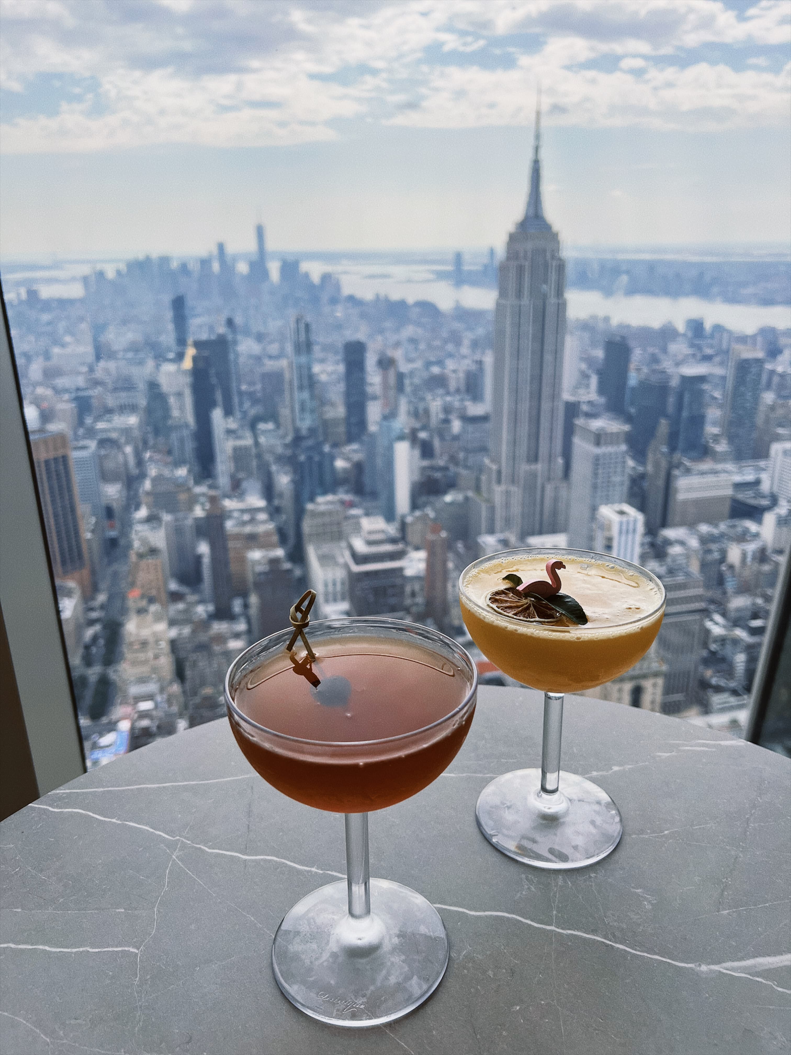Two cocktails on a small table overlooking the Manhattan skyline