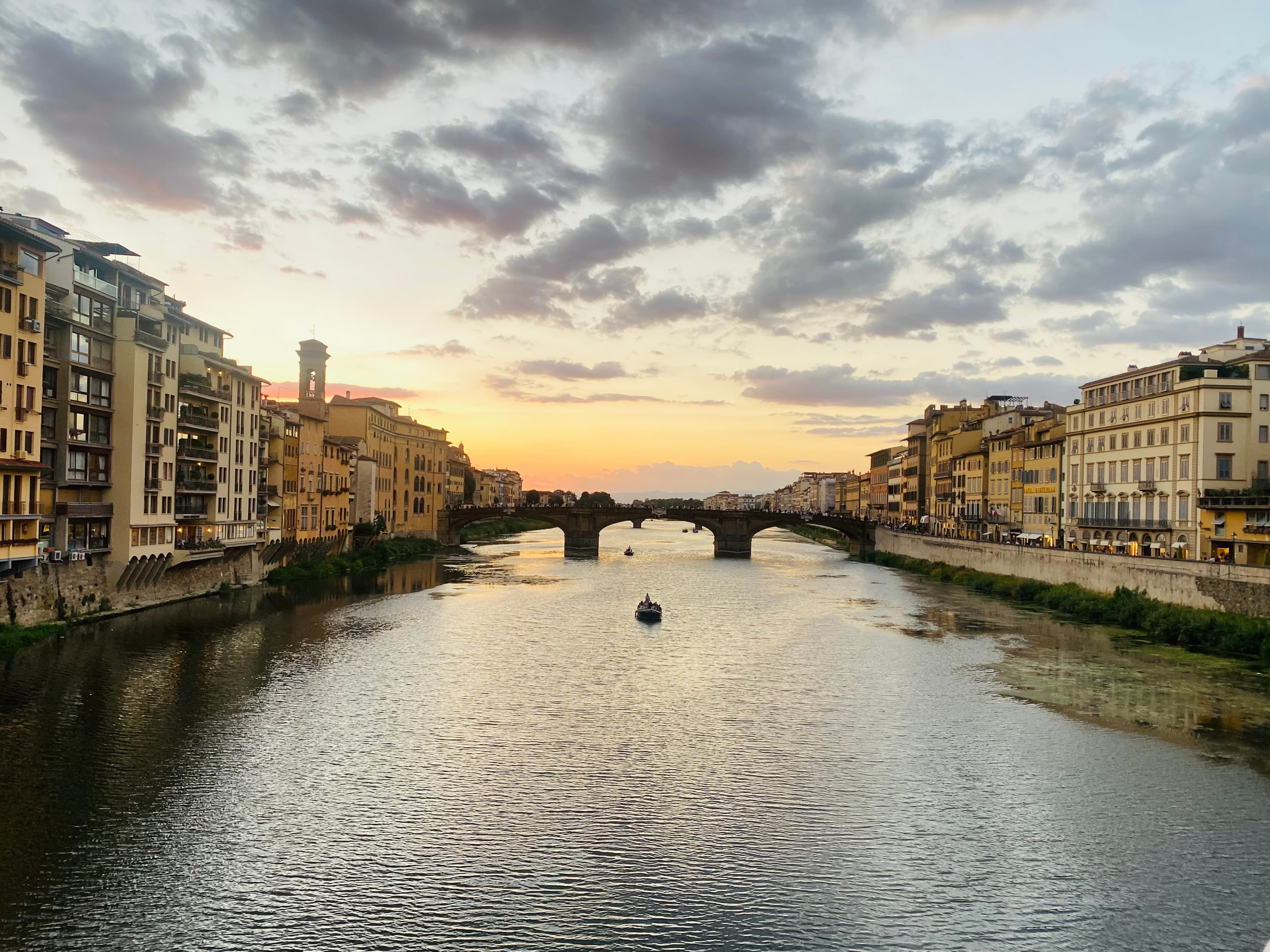 Beautiful view of a calm river with a bridge connecting two sides of a city at sunset