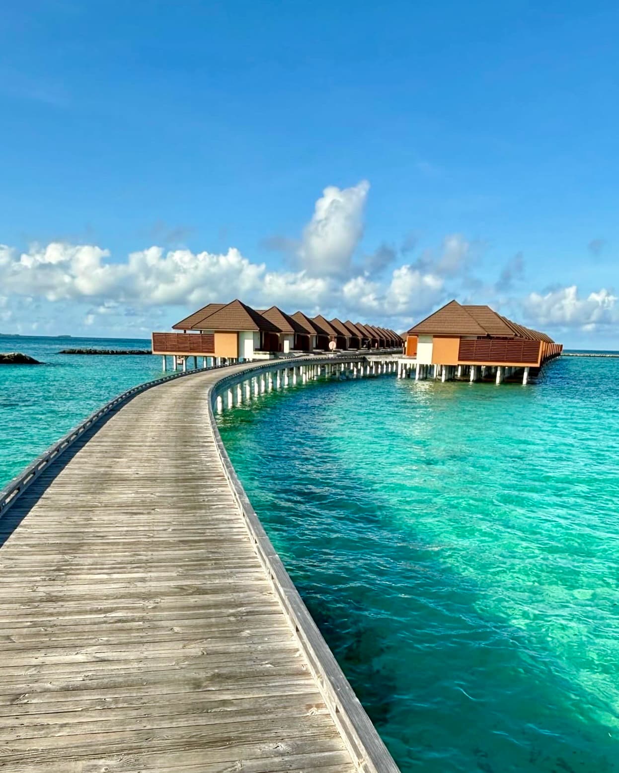 View of a wooden path leading to overwater bungalows on a sunny day