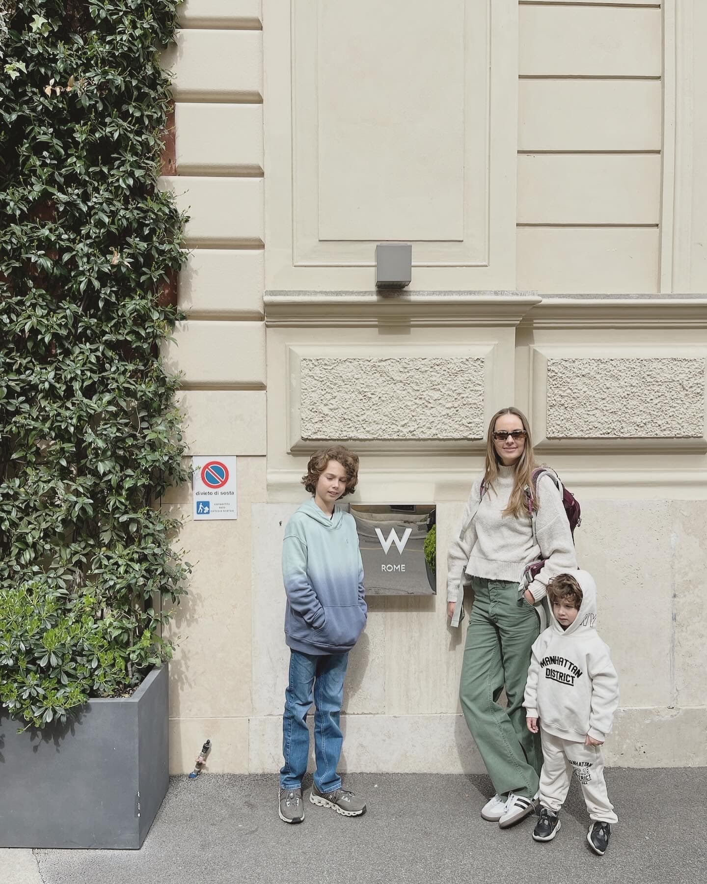 Standing by a cream wall.