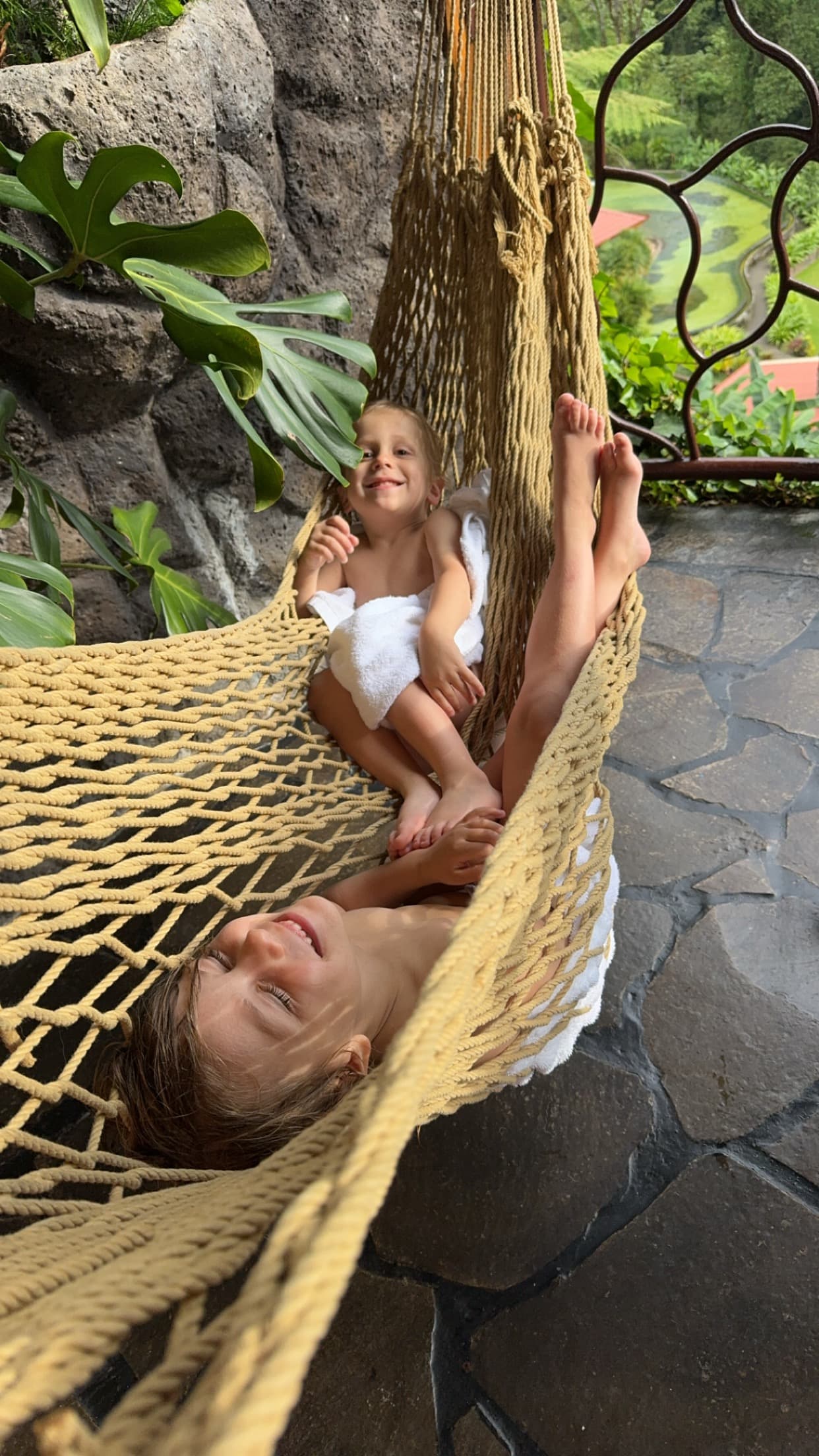 Two children lying in a hammock laughing.
