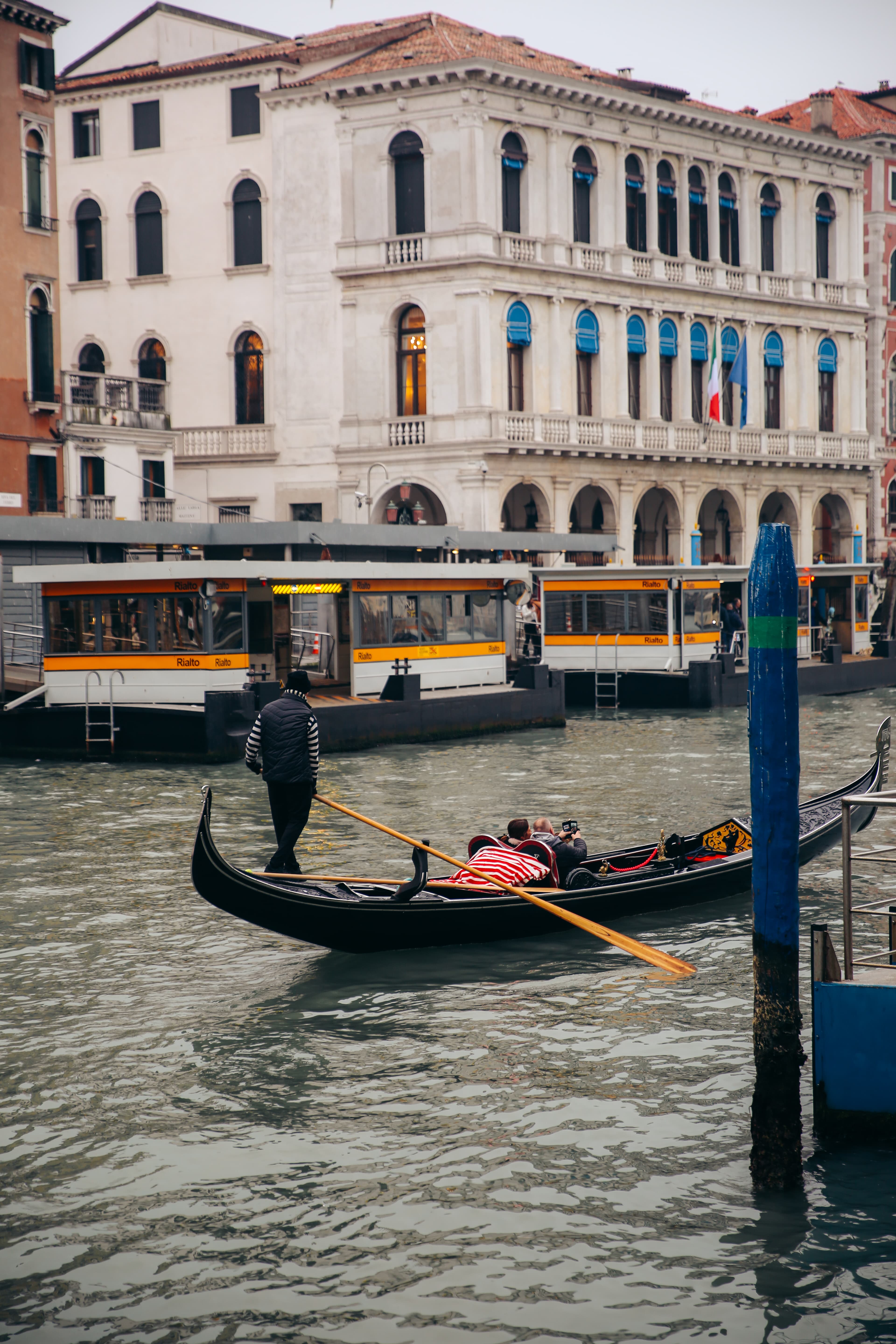 A view of the Venice canal with someone rowing a boat and old Italian buildings in the background.