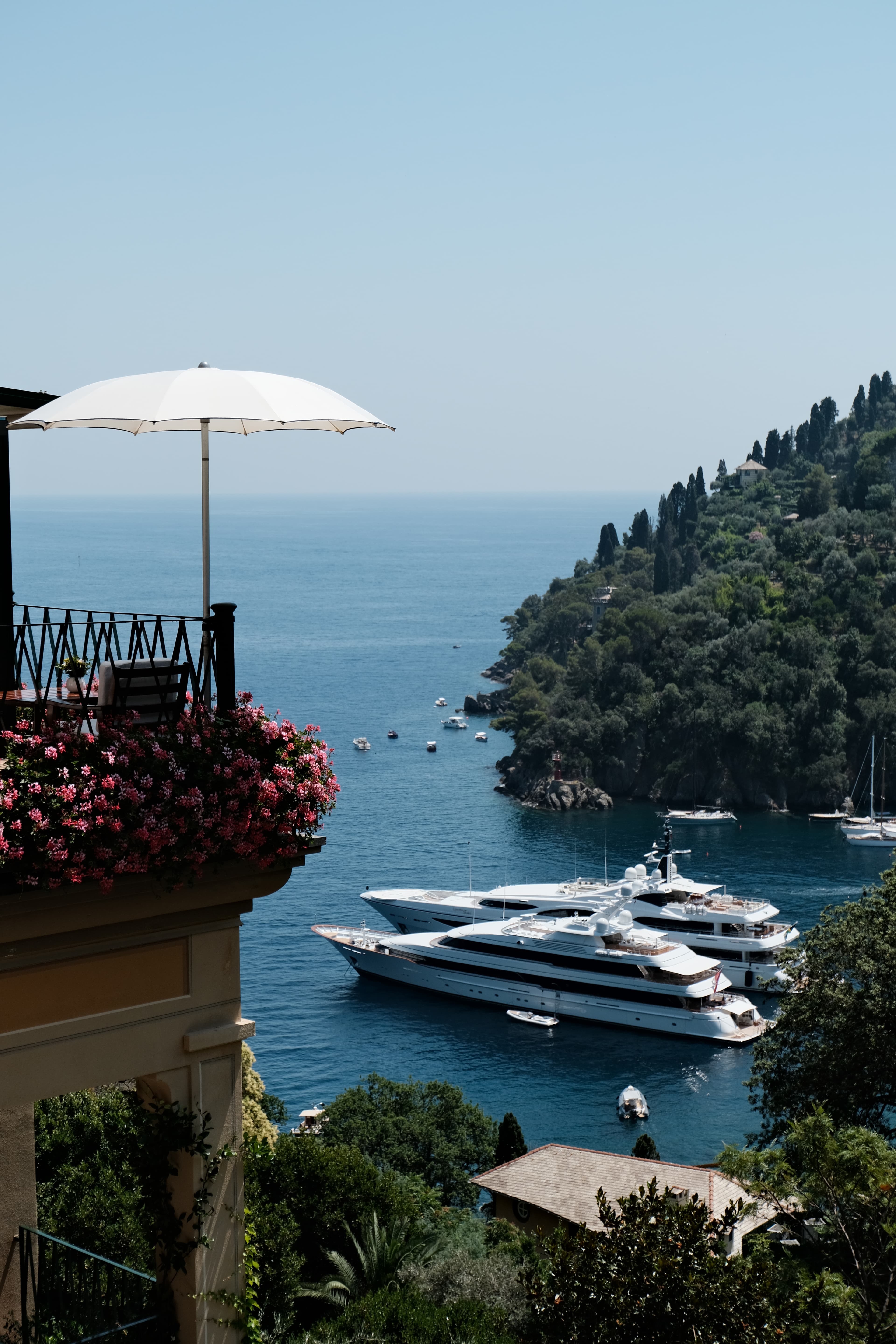 A view of a harbor with luxury yachts and a white umbrella in sight.