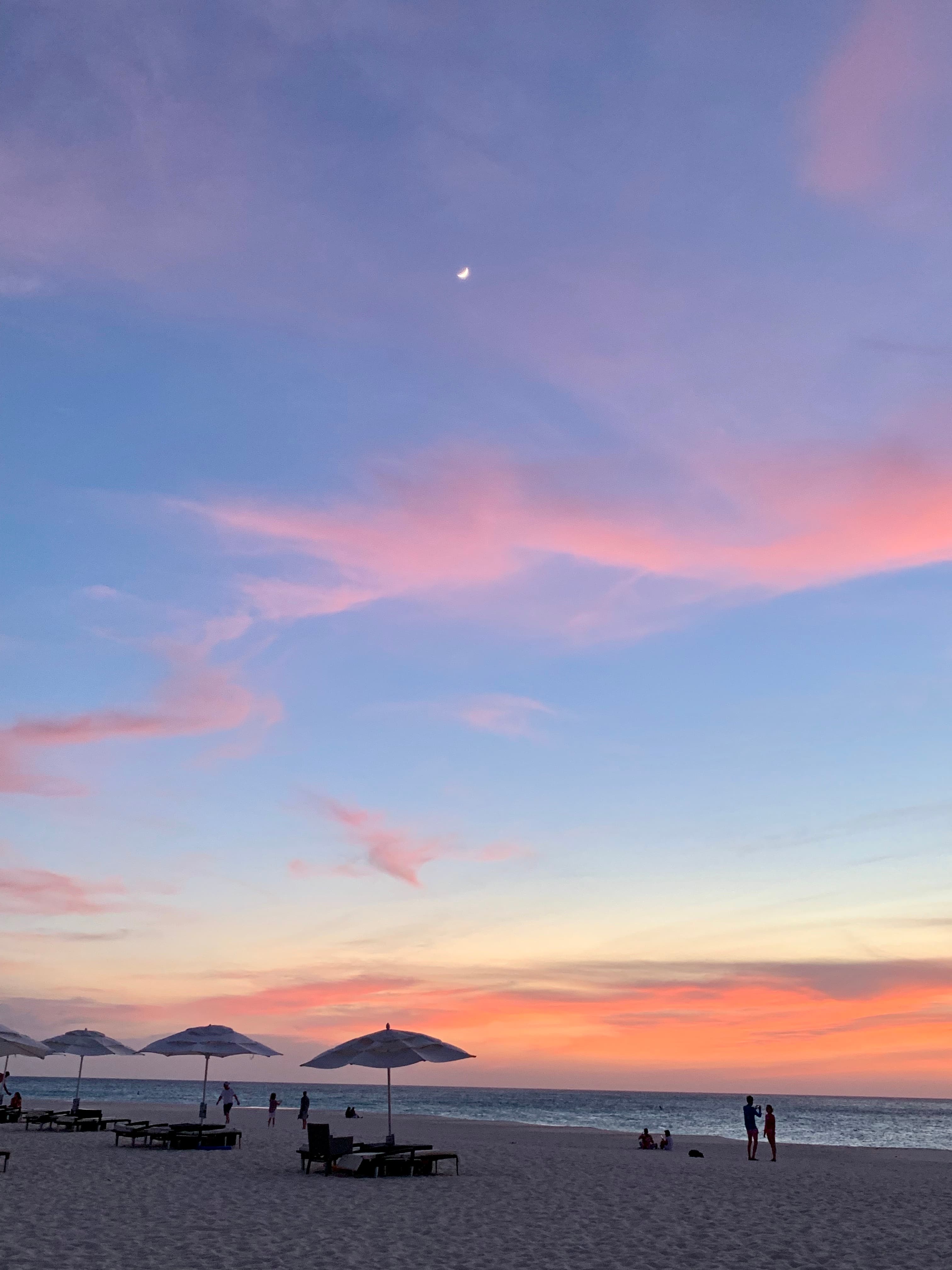 Beautiful view of a pastel sunset over a beach with umbrellas in the sand